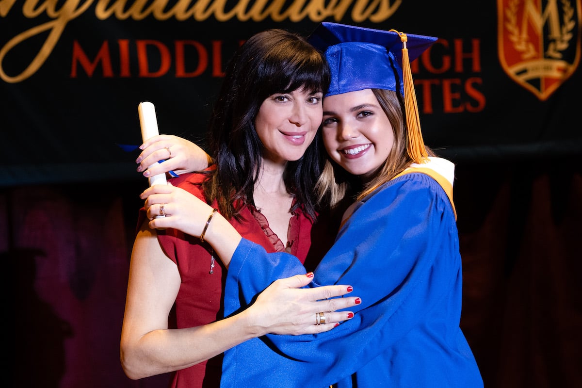 Grace, wearing a cap and gown, with her arms around Cassie in Good Witch 
