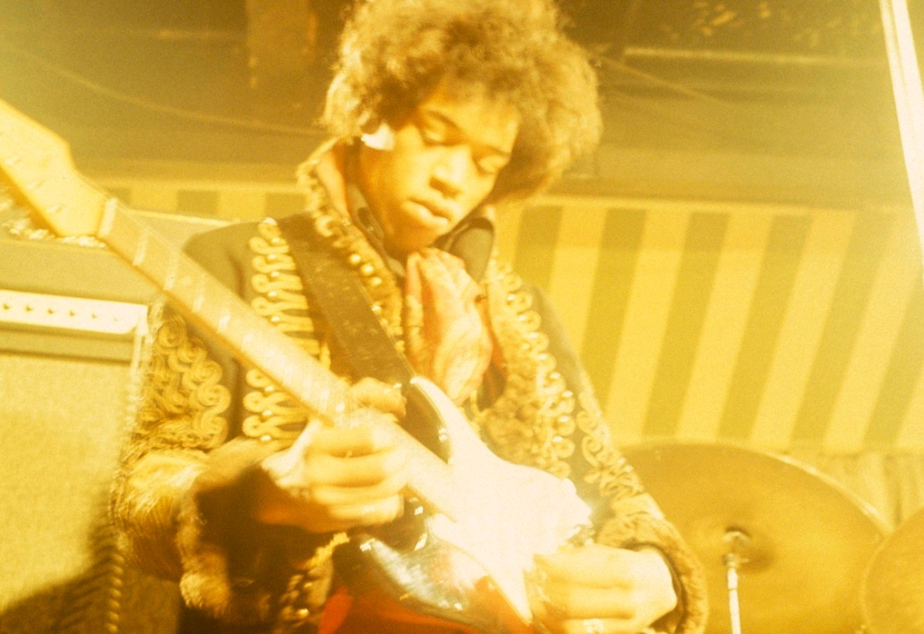 Jimi Hendrix plays guitar on stage in 1967.