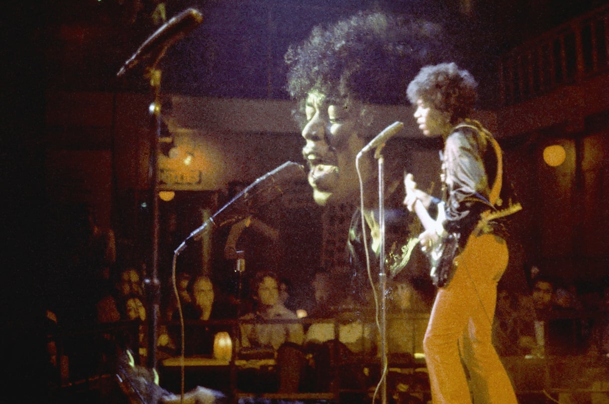 Jimi Hendrix performs on a stage in front of an audience