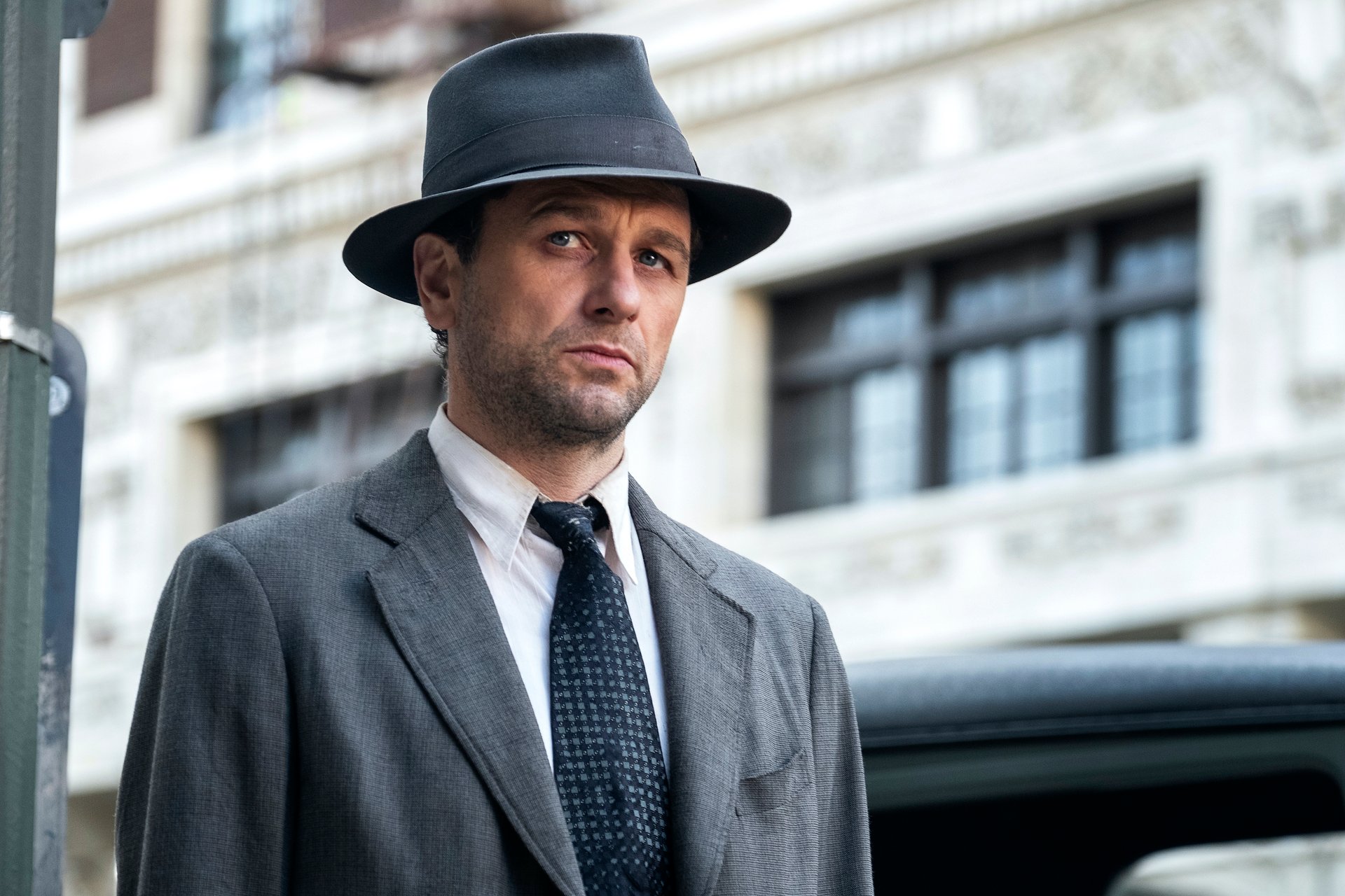 Matthew Rhys as Perry Mason wearing a gray fedora
