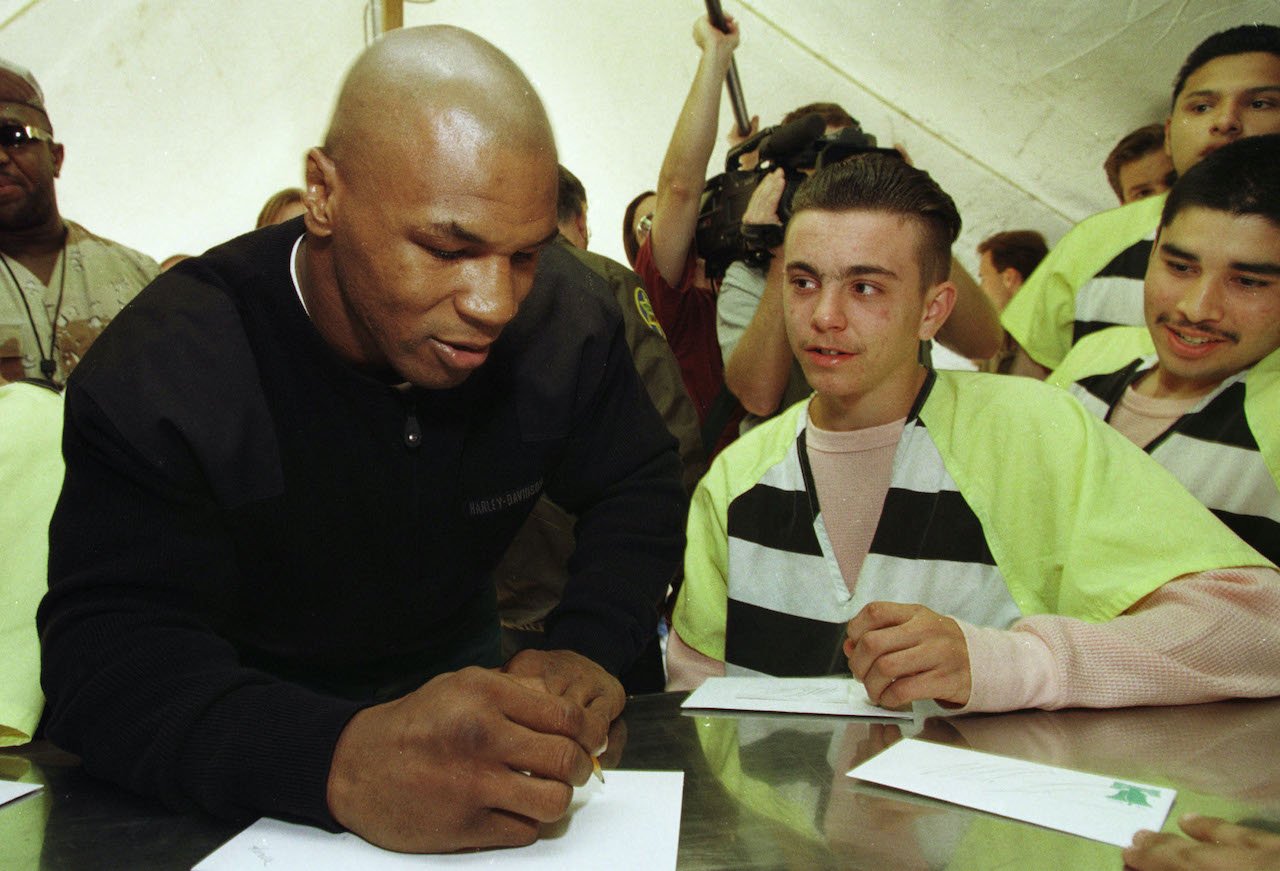 Teenage inmate Philip Hagadorn, center, watches as former heavyweight boxing champion Mike Tyson signs autographs at the Maricopa County "Pup Tent City" jail facility