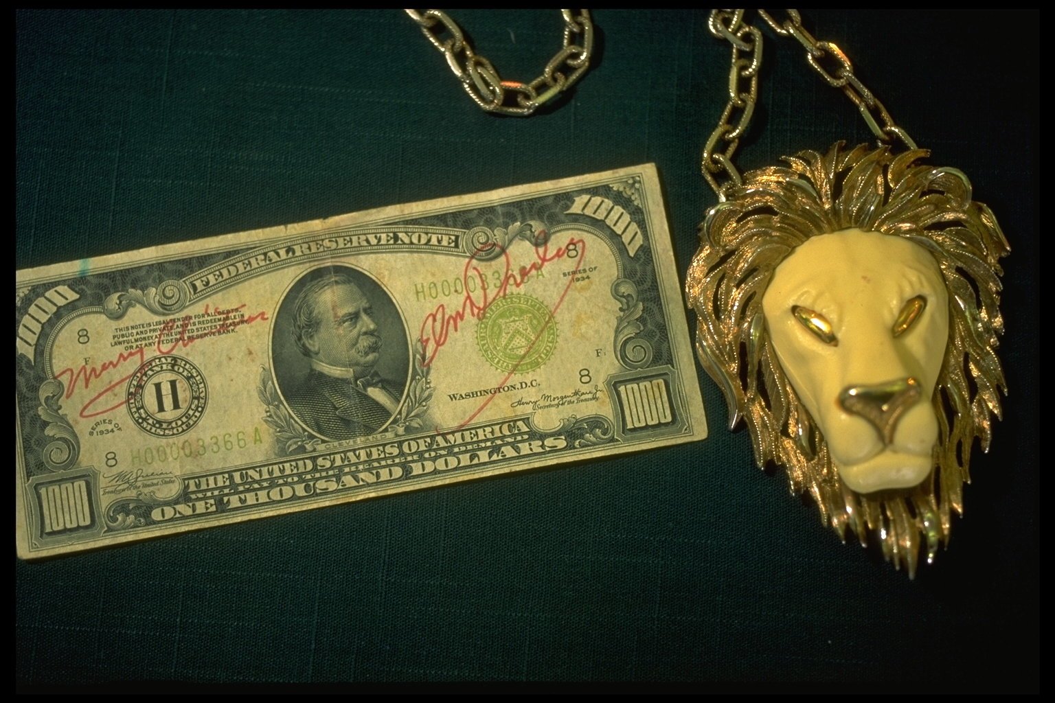 A thousand dollar bill owned by Elvis Presley next to a lion necklace