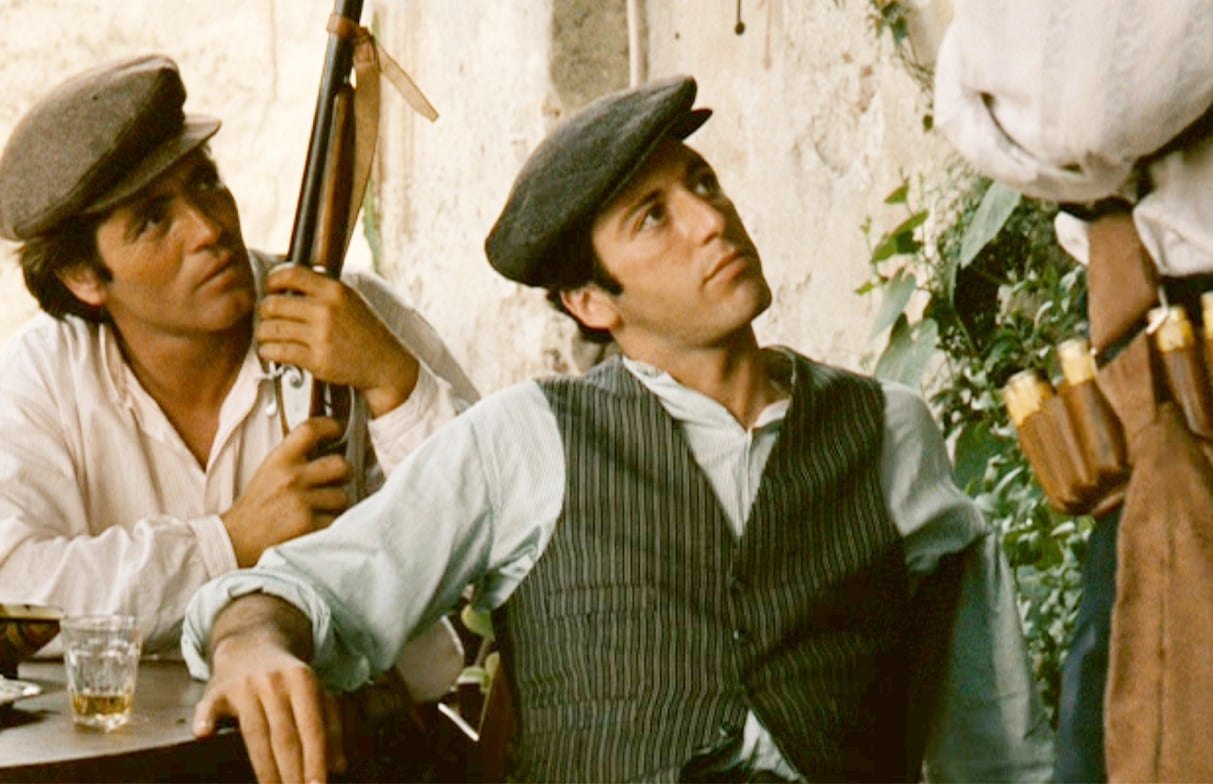 Franco Citti as Calo holds a gun and Al Pacino as Michael Corleone looks up in 'The Godfather'