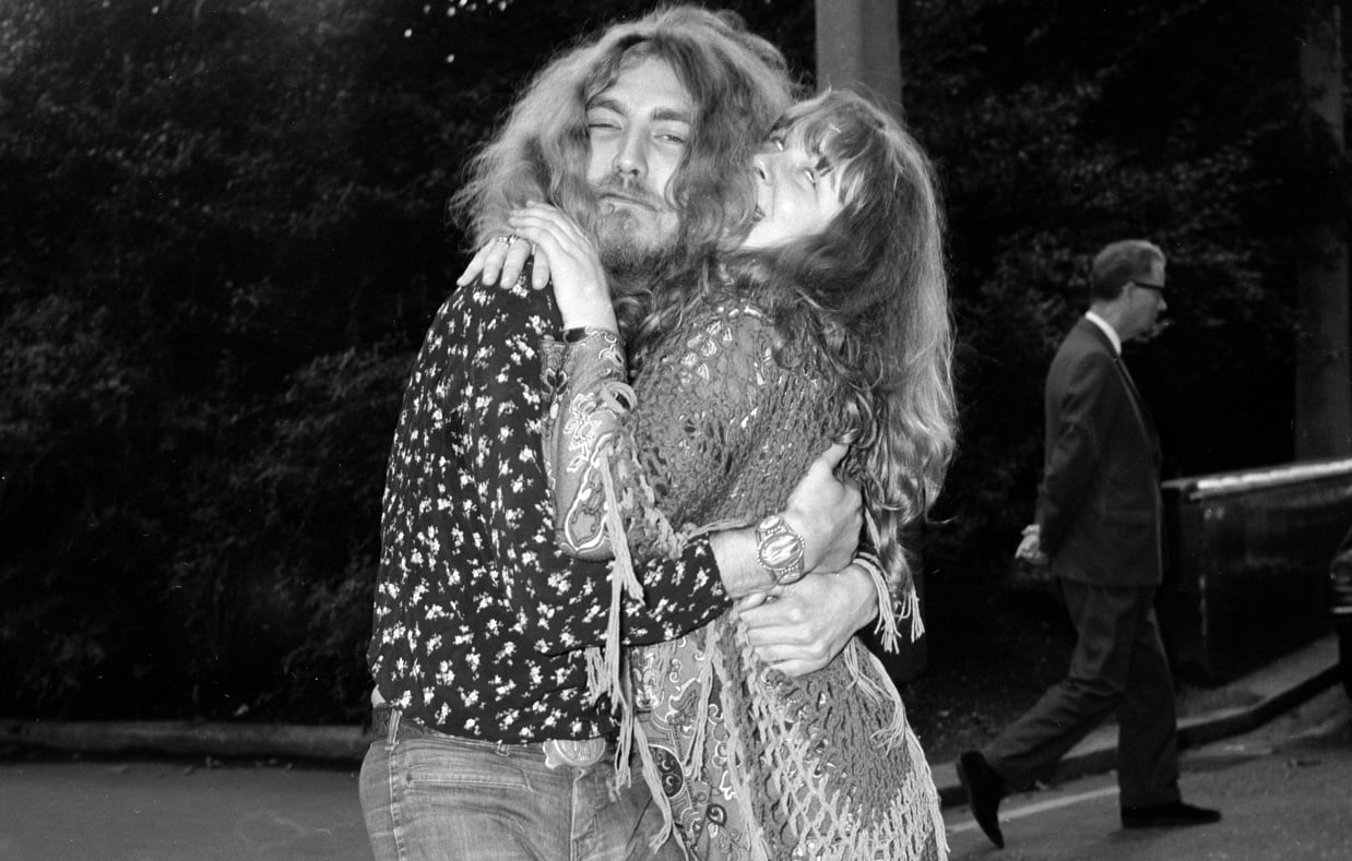 Robert Plant and Sandy Denny hugging in front of a park
