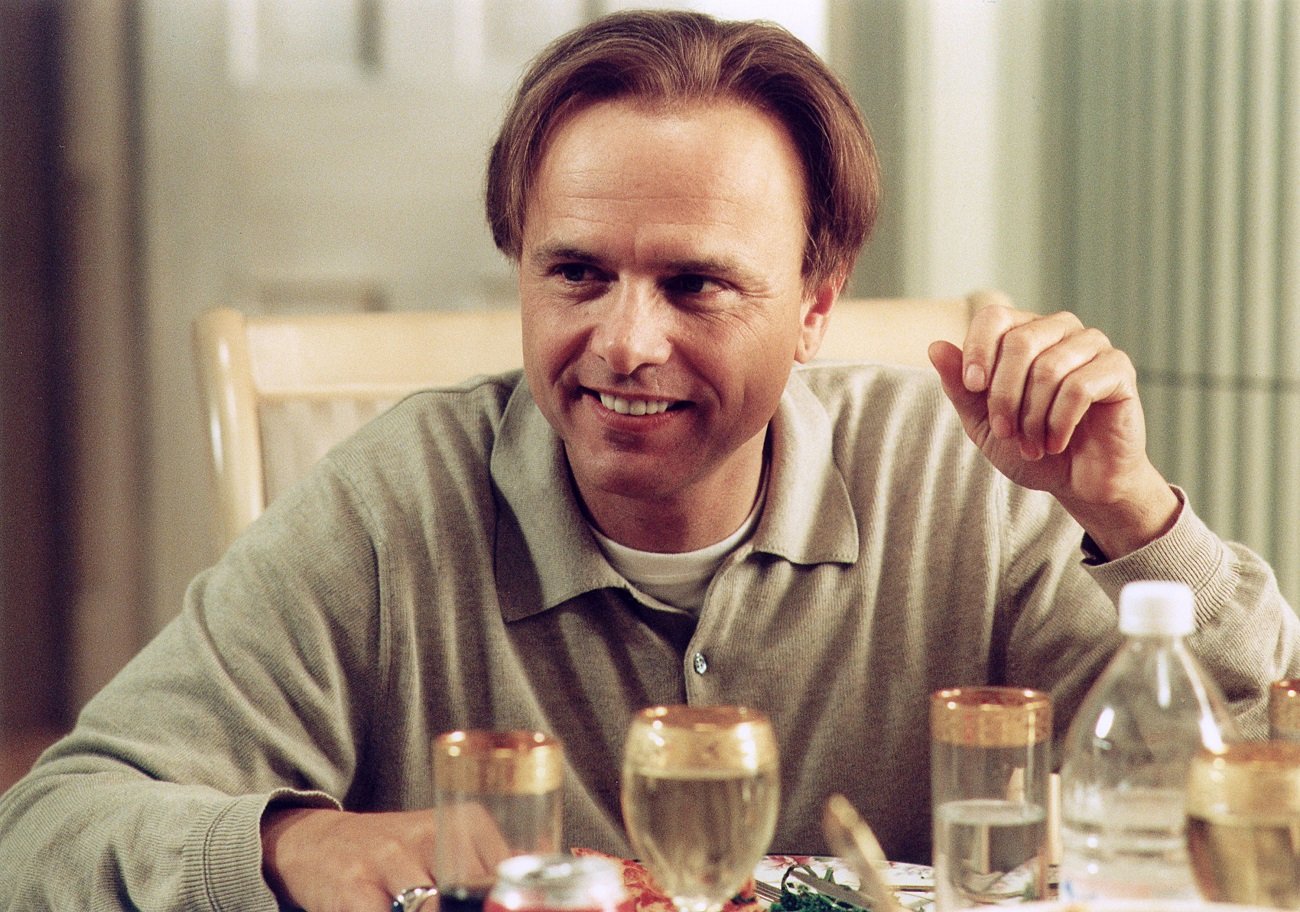 Joe Pantoliano smiles in character as Ralph Cifaretto seated at the dinner table