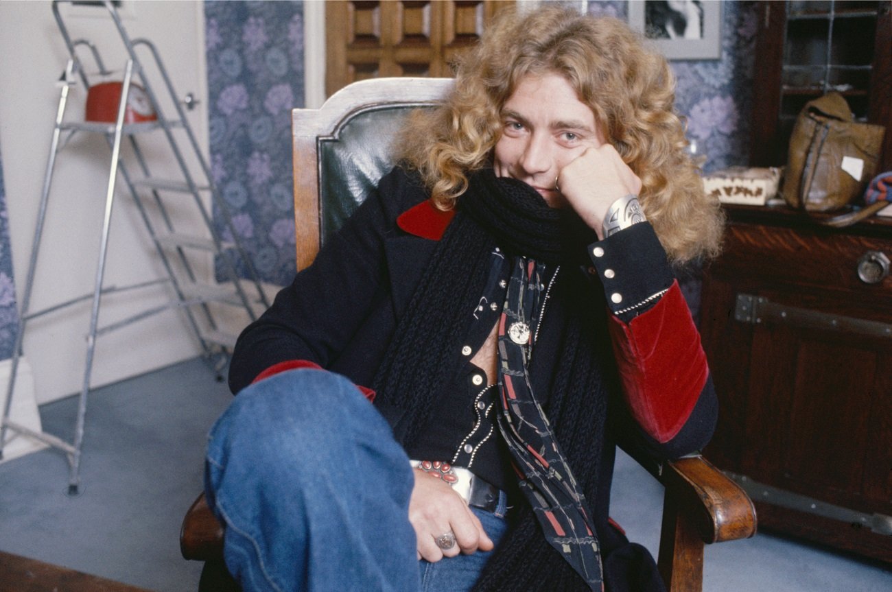 A seated Robert Plant smiles and looks at the camera in 1975.