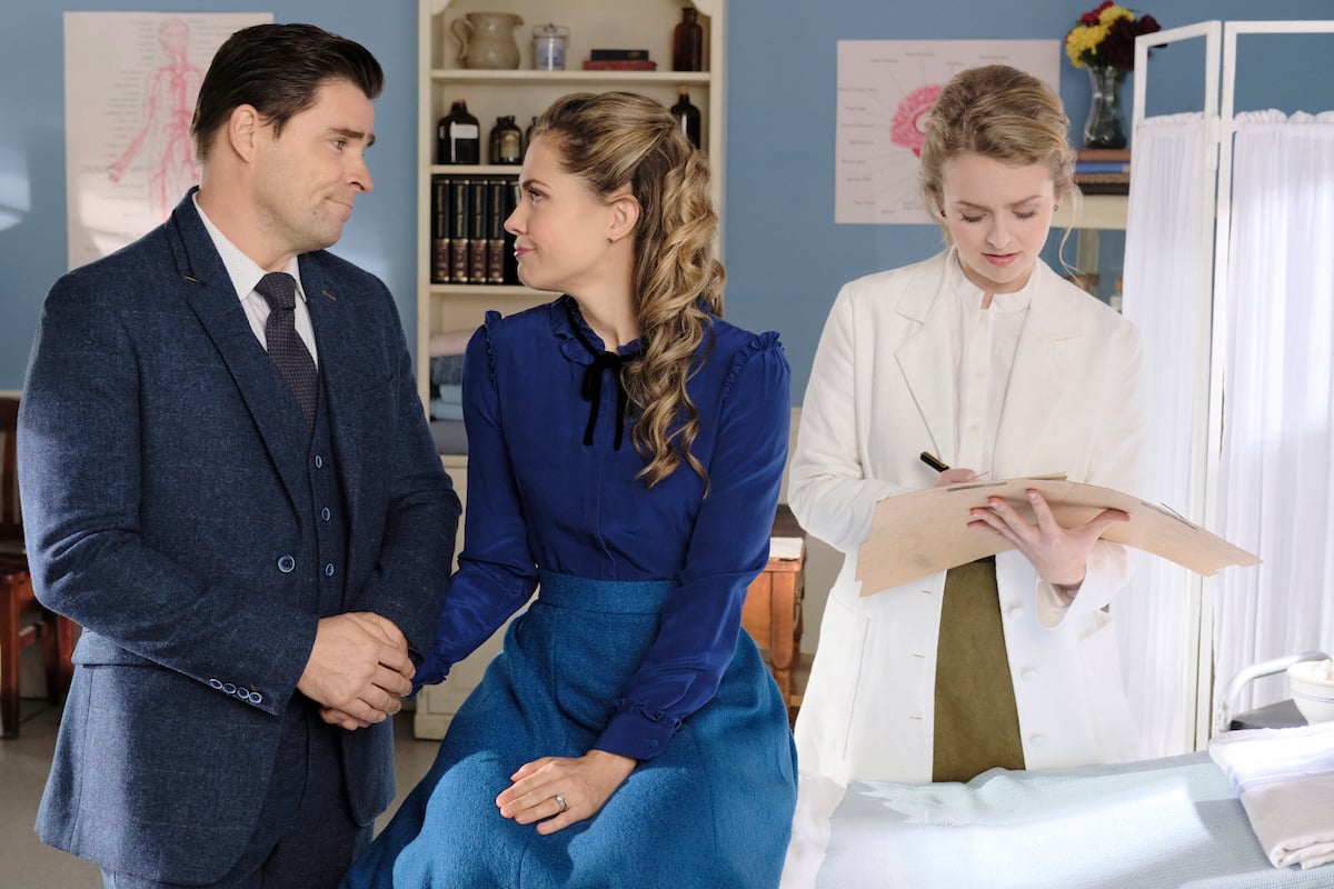 Rosemary and Lee holding hands while Faith makes notes in an episode of When Calls the Heart
