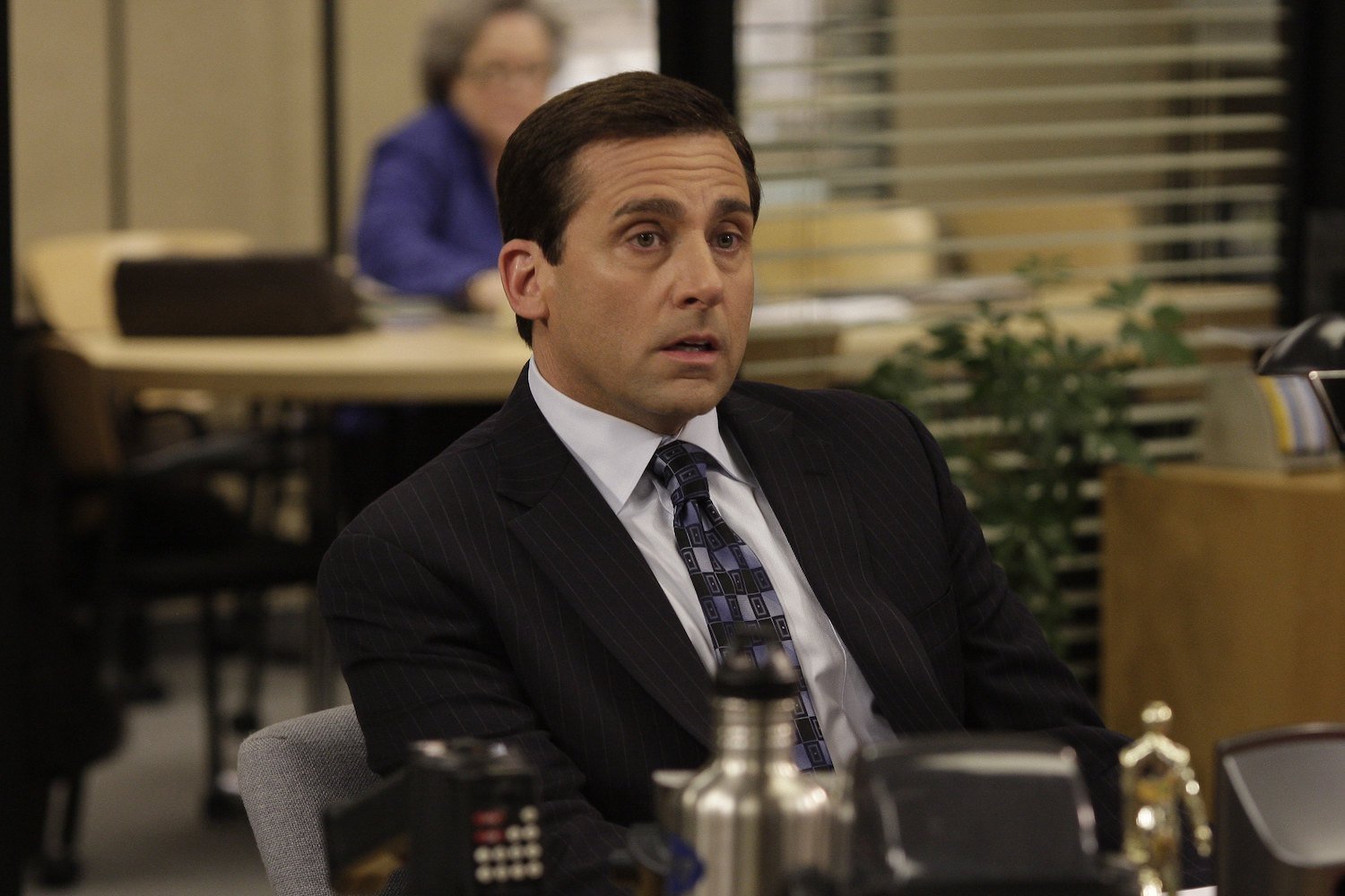 The Office Steve Carell sits at a desk in character as Michael Scott