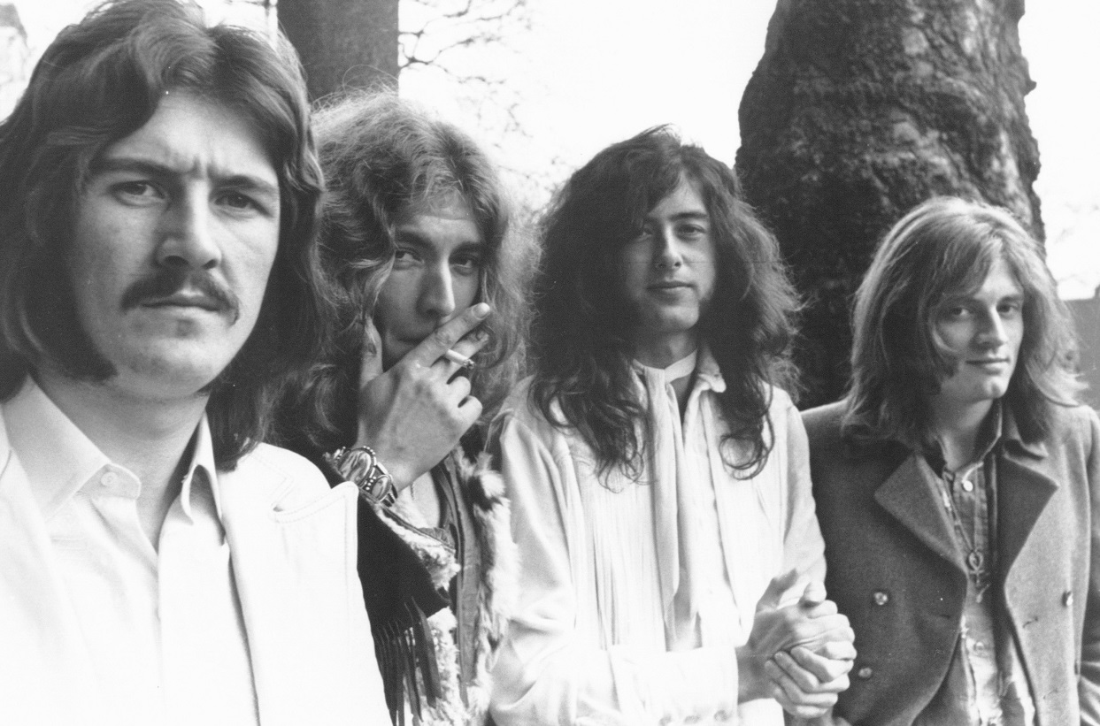 John Bonham scowls as the other members of Led Zeppelin smile for the camera