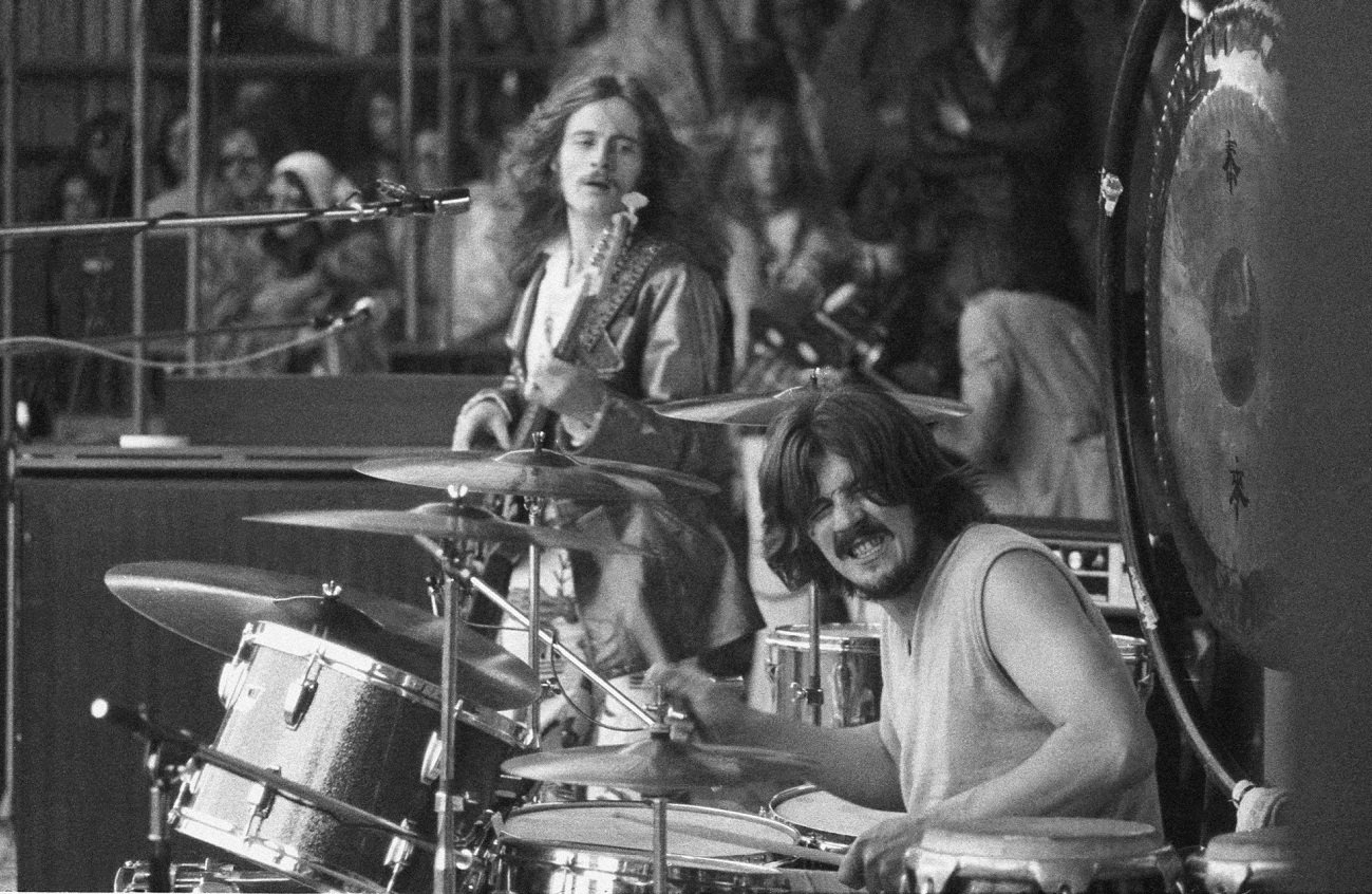 John Paul Jones playing bass looks over at John Bonham playing drums on stage at an outdoor festival
