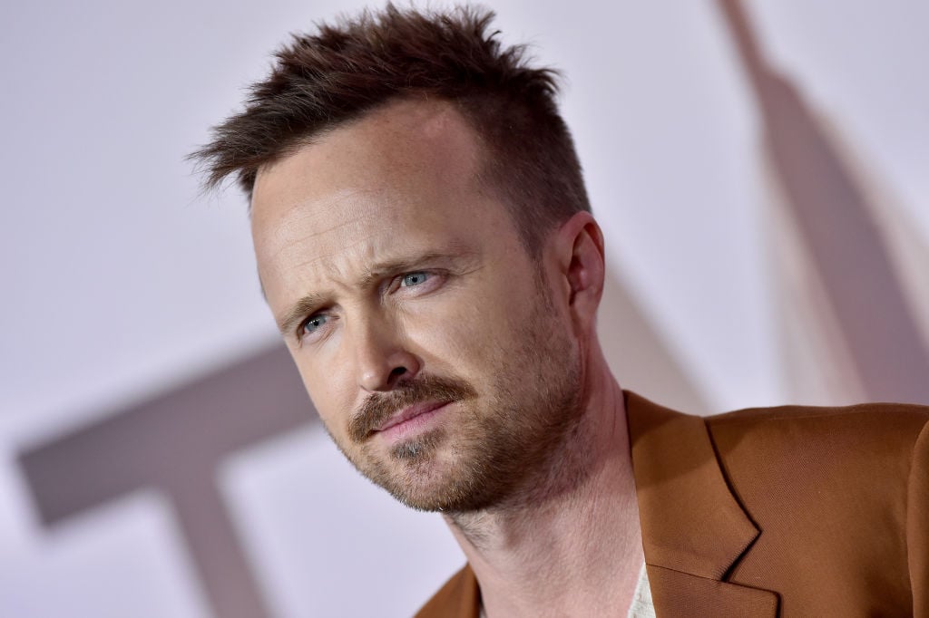 Aaron Paul walks to red carpet in a brown suit.