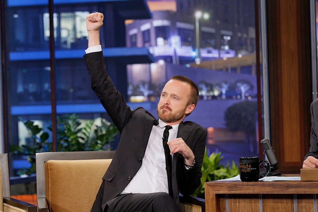 Actor Aaron Paul looks excited with an arm up in the air during an interview with Jay Leno.