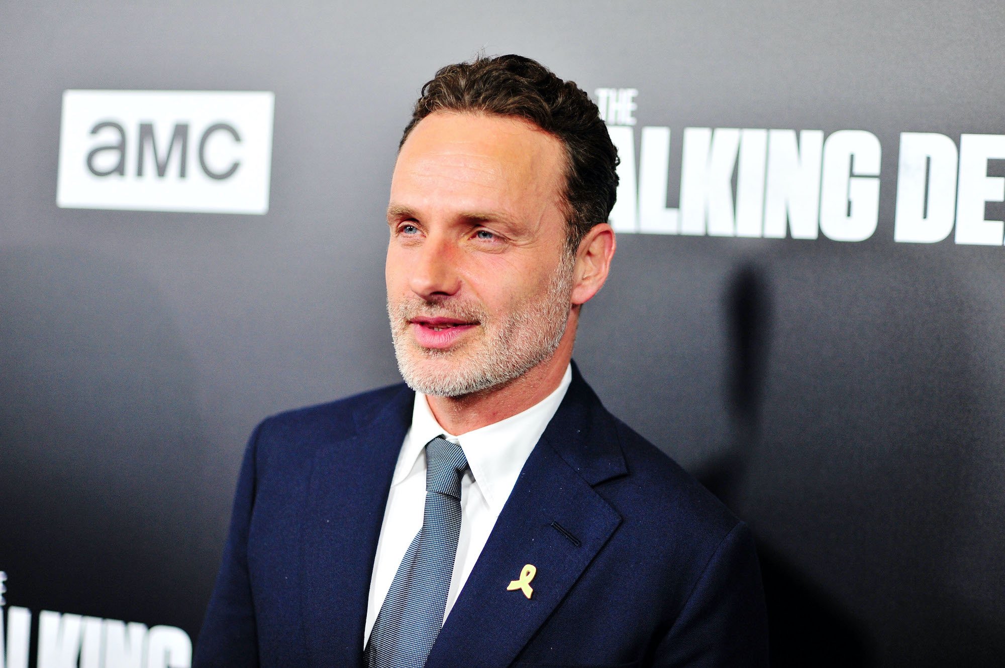 Andrew Lincoln smiling in front of a black background
