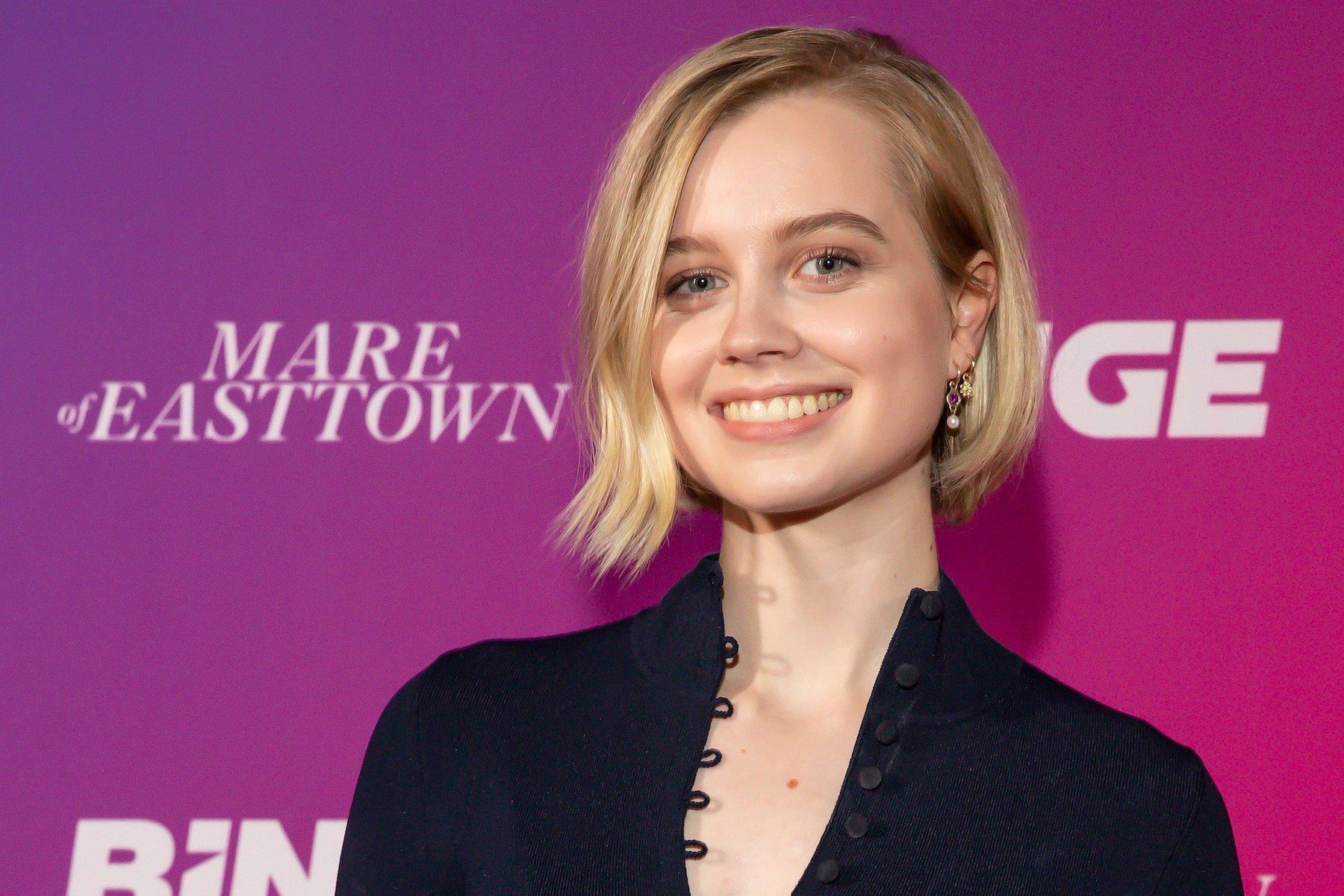 Angourie Rice smiling in front of a pink background