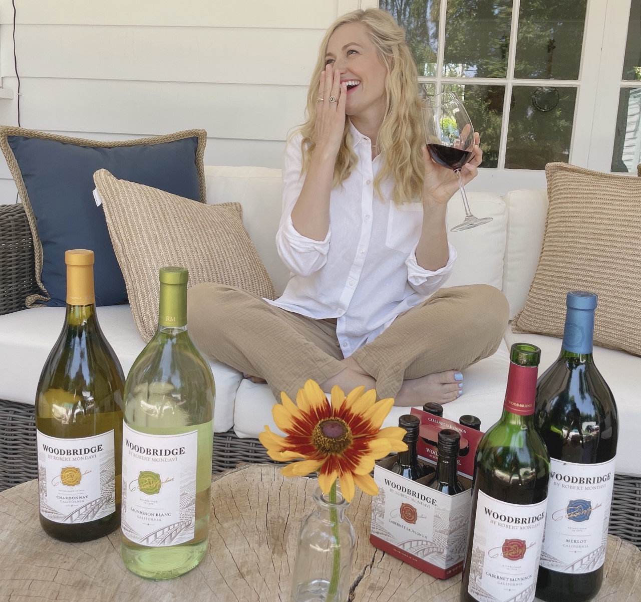 Beth Behrs smiling and holding glass of red wine with her hand over her mouth
