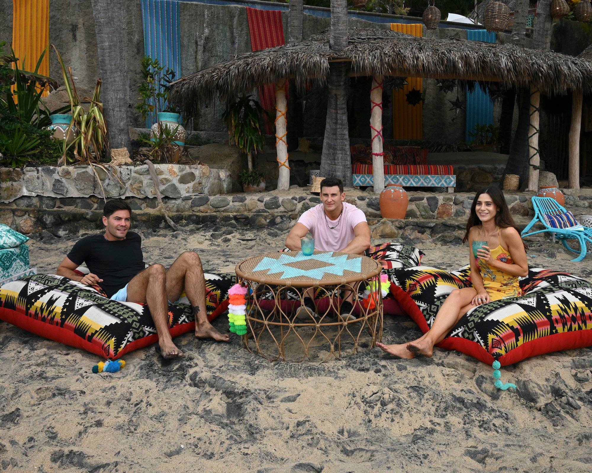 Bachelor In Paradise cast members gathered around a fire pit on a beach