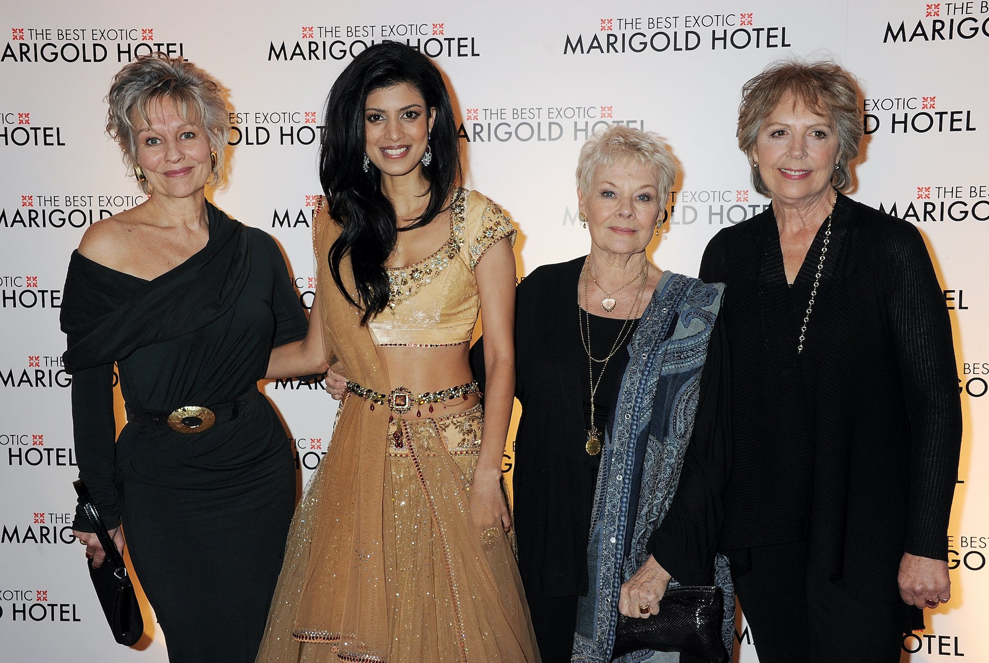 Cast members of 'The Best Exotic Marigold Hotel' smiling in front of a white background