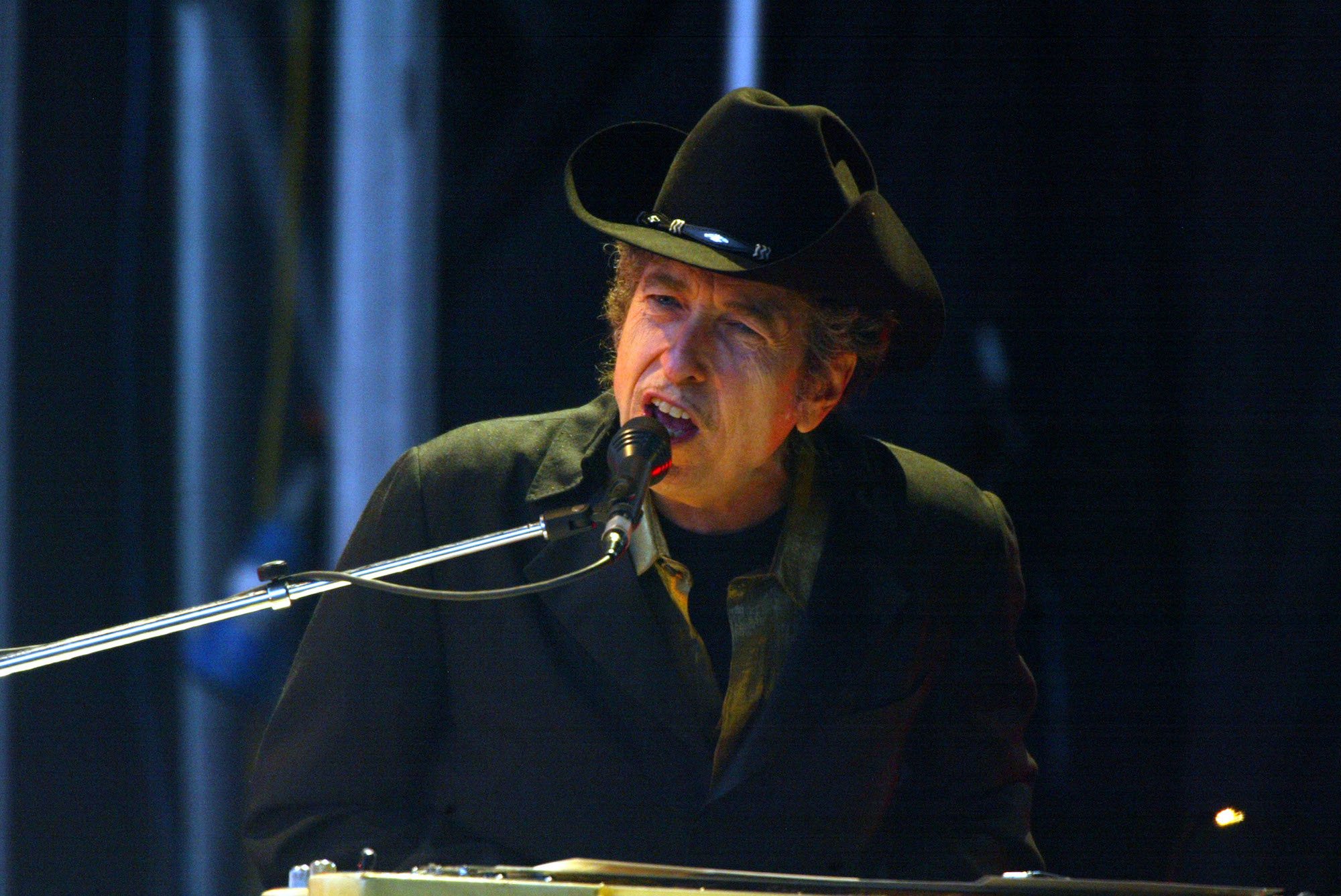 Bob Dylan singing into a microphone, seating