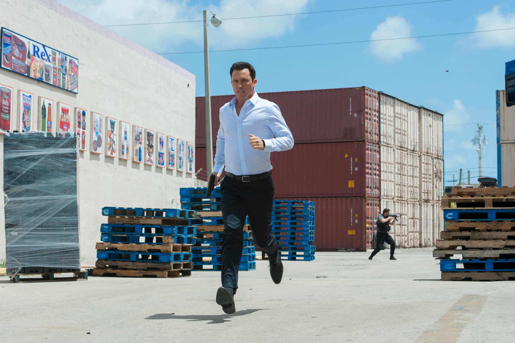 Jeffrey Donovan running, carrying a gun in 'Burn Notice'