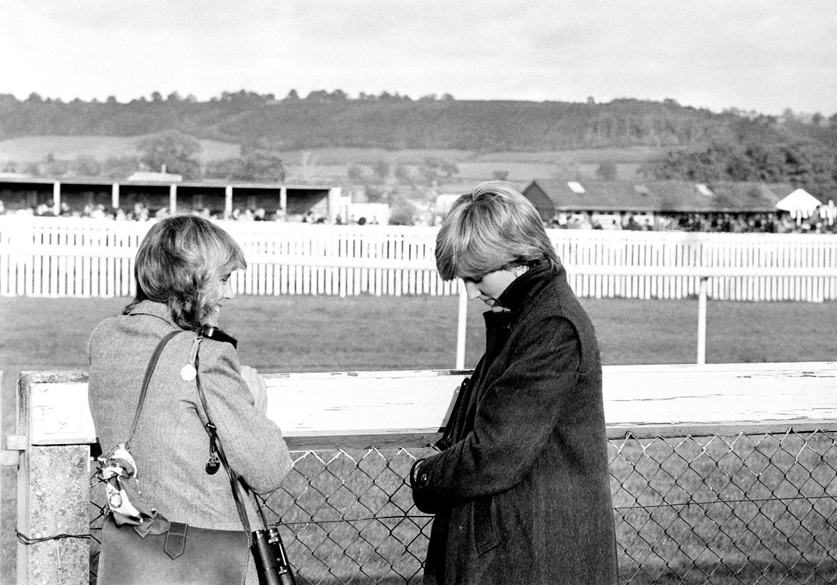 Camilla Parker Bowles and Lady Diana Spencer (later the Princess Diana) standing next to a fence at Ludlow racecourse