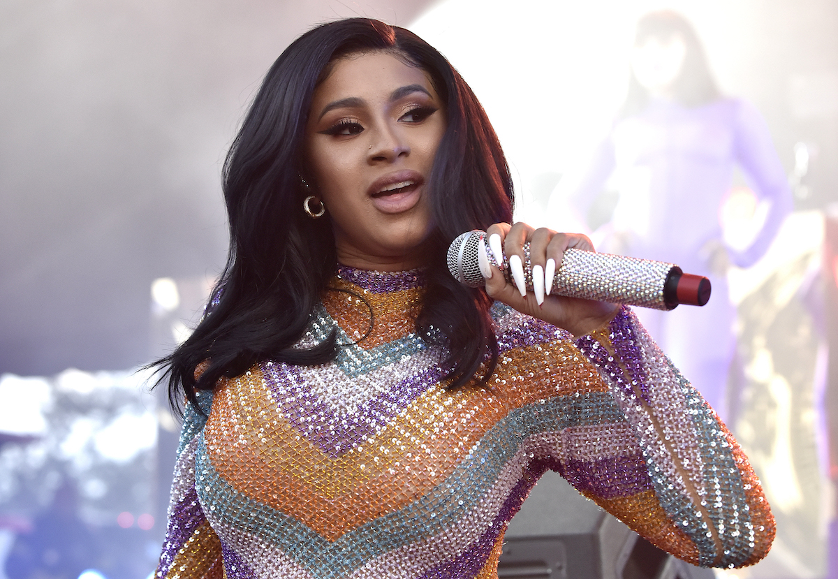 Cardi B holds a microphone while performing on stage.