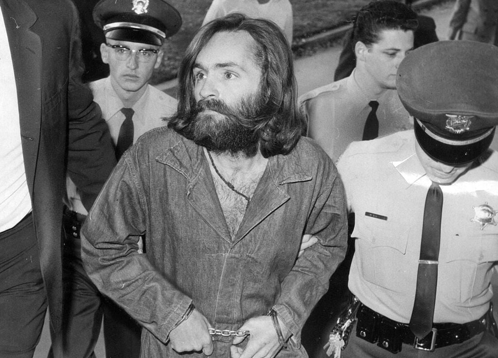 Charles Manson is escorted to court for preliminary hearing. He is dressed in a jumpsuit and shackles.