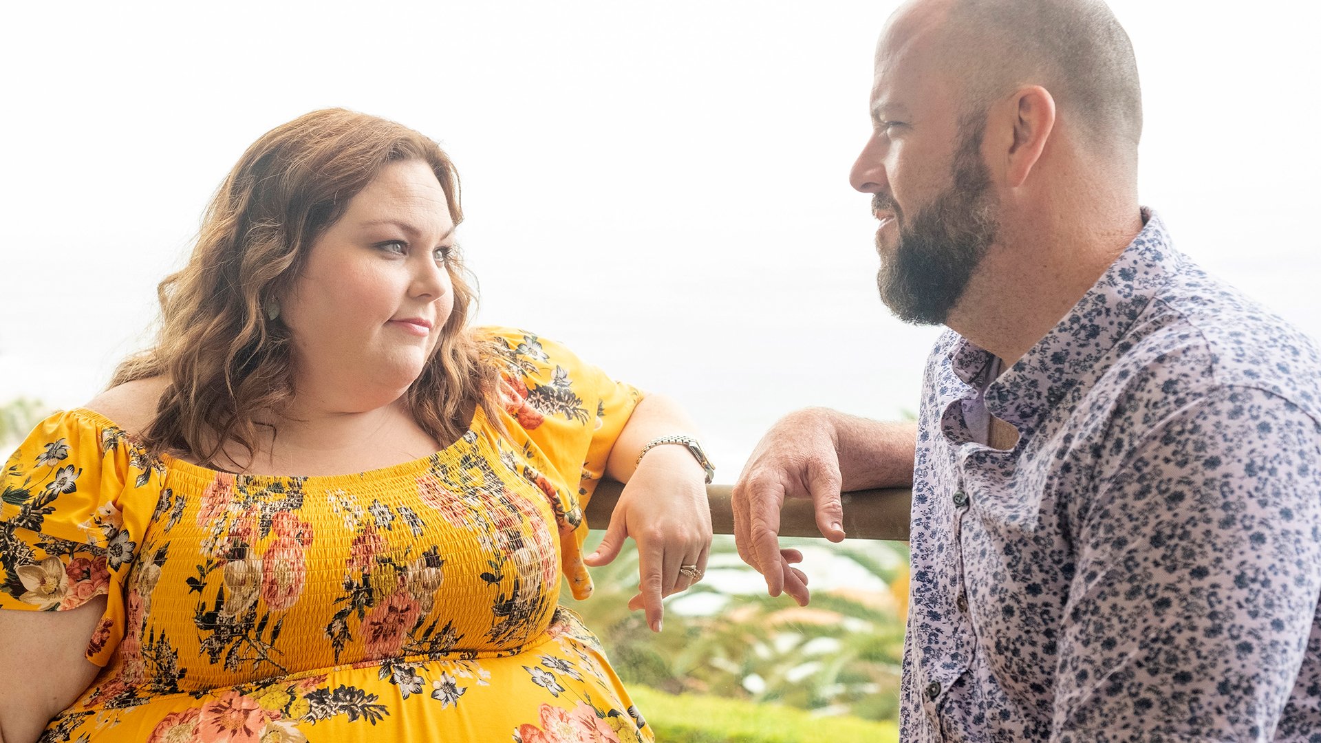 Chrissy Metz wears a yellow floral dress as she looks at Chris Sullivan in a scene from ‘This Is Us’ Season 5