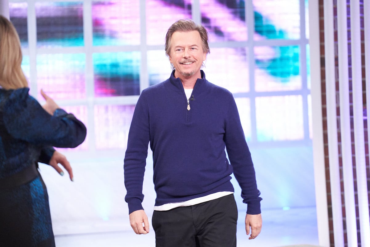 David Spade in a blue sweater and black pants
