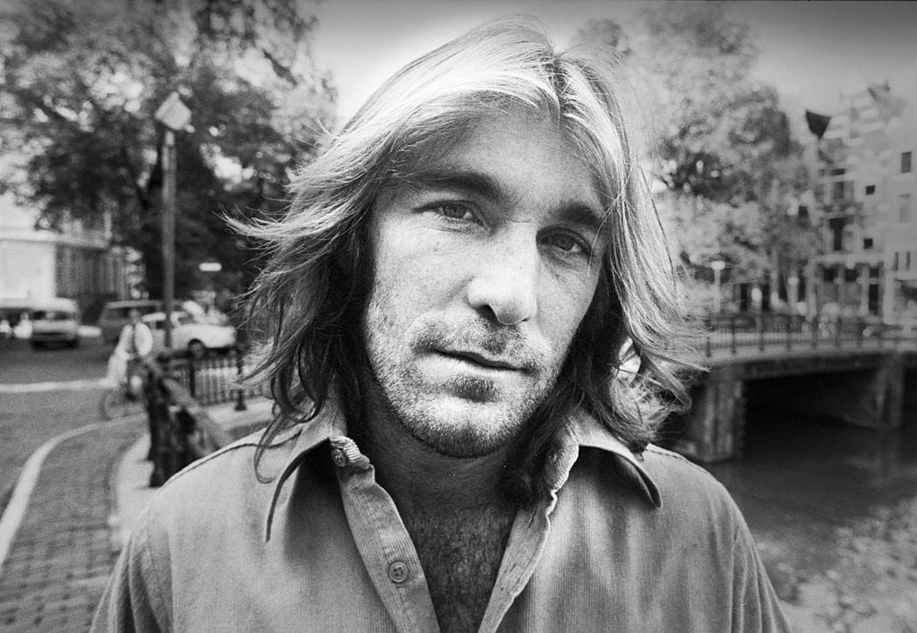 Black and white portrait of Beach Boys drummer Dennis Wilson looking into the camera with a deadpan stare.