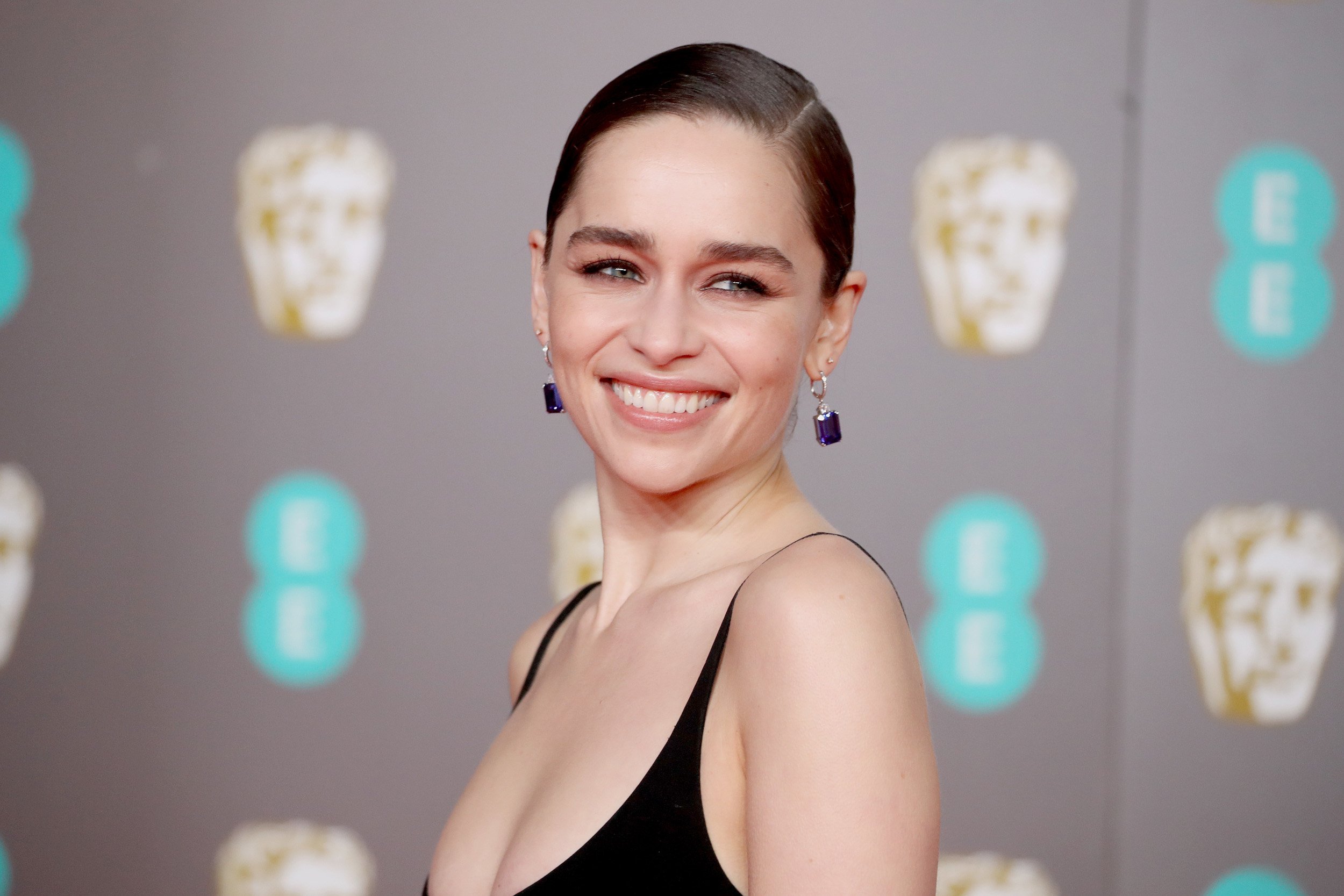 Emilia Clarke with her hair pulled back and wearing a black dress at the EE British Academy Film Awards