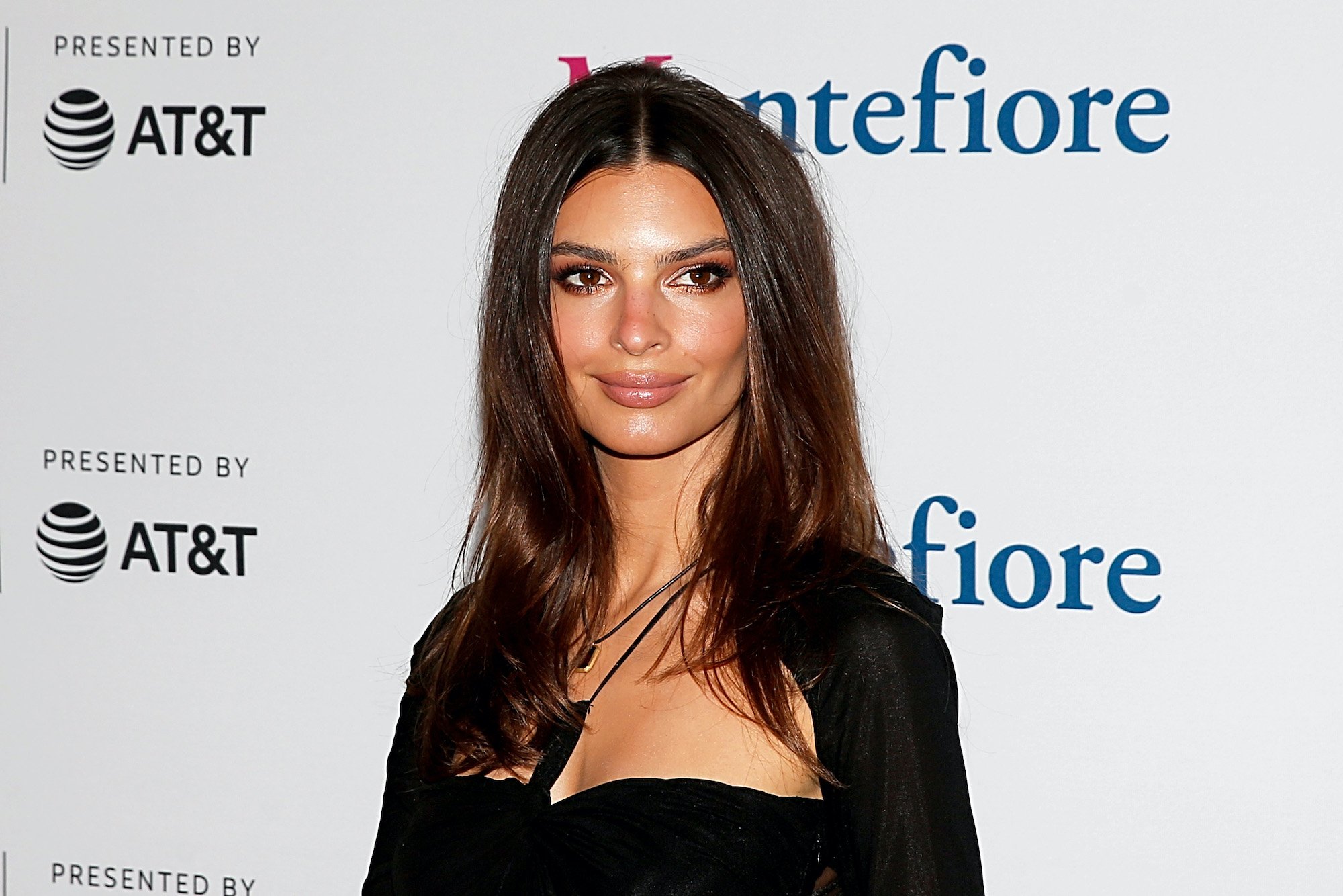 Emily Ratajkowski smiling in front of a white background