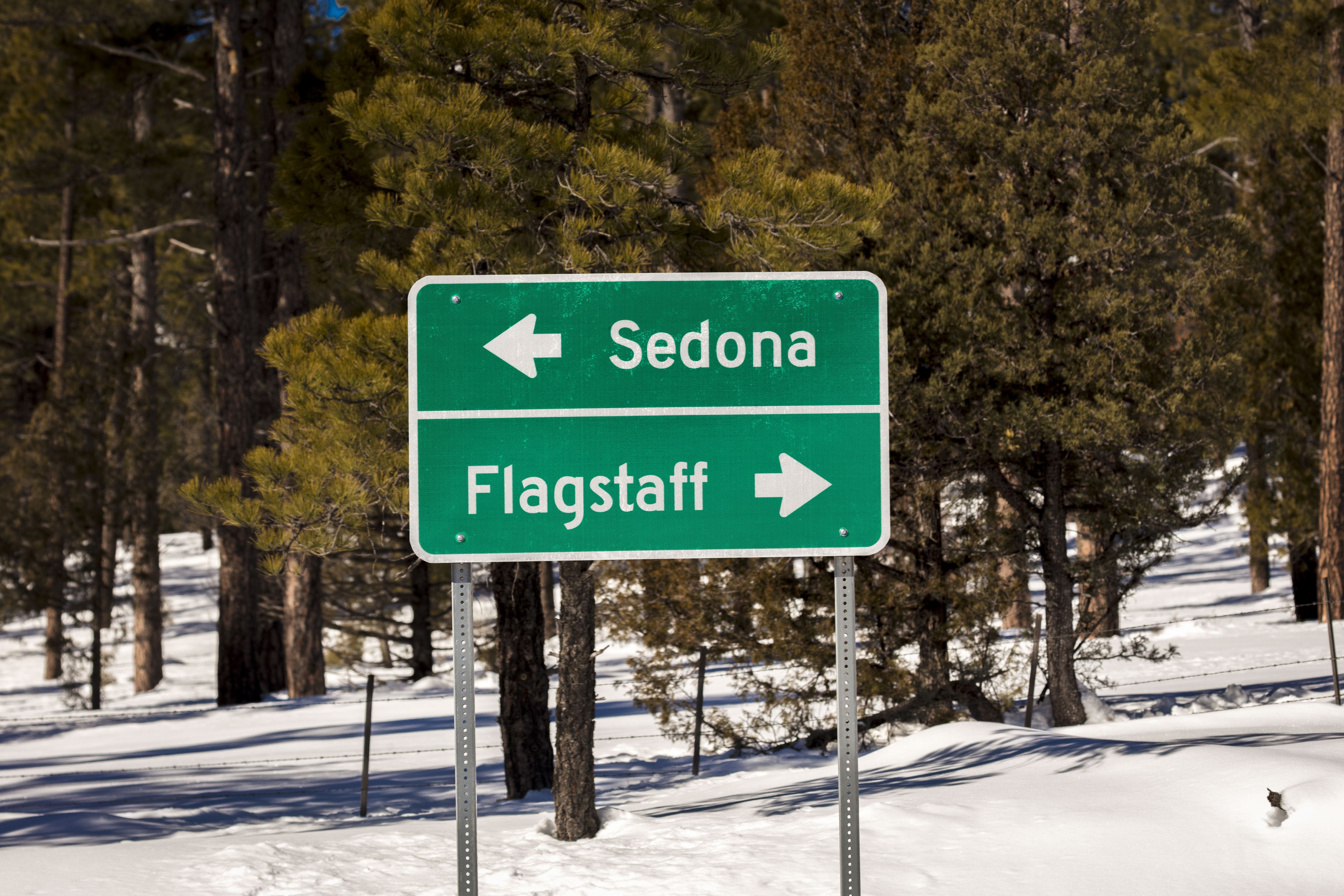 A standard road sign shows the way to Flagstaff Arizona and Sedona