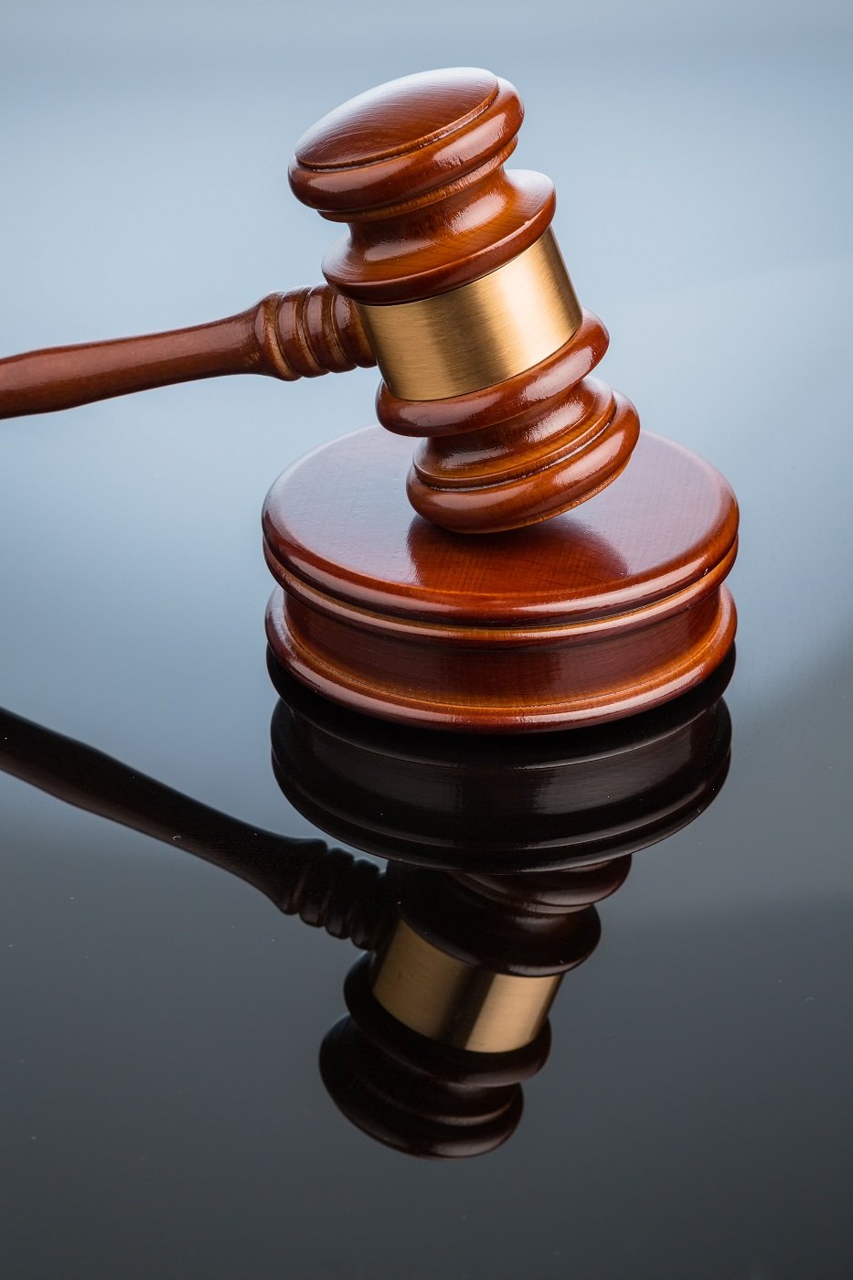 A judge's gavel is seen on a shiny black desk