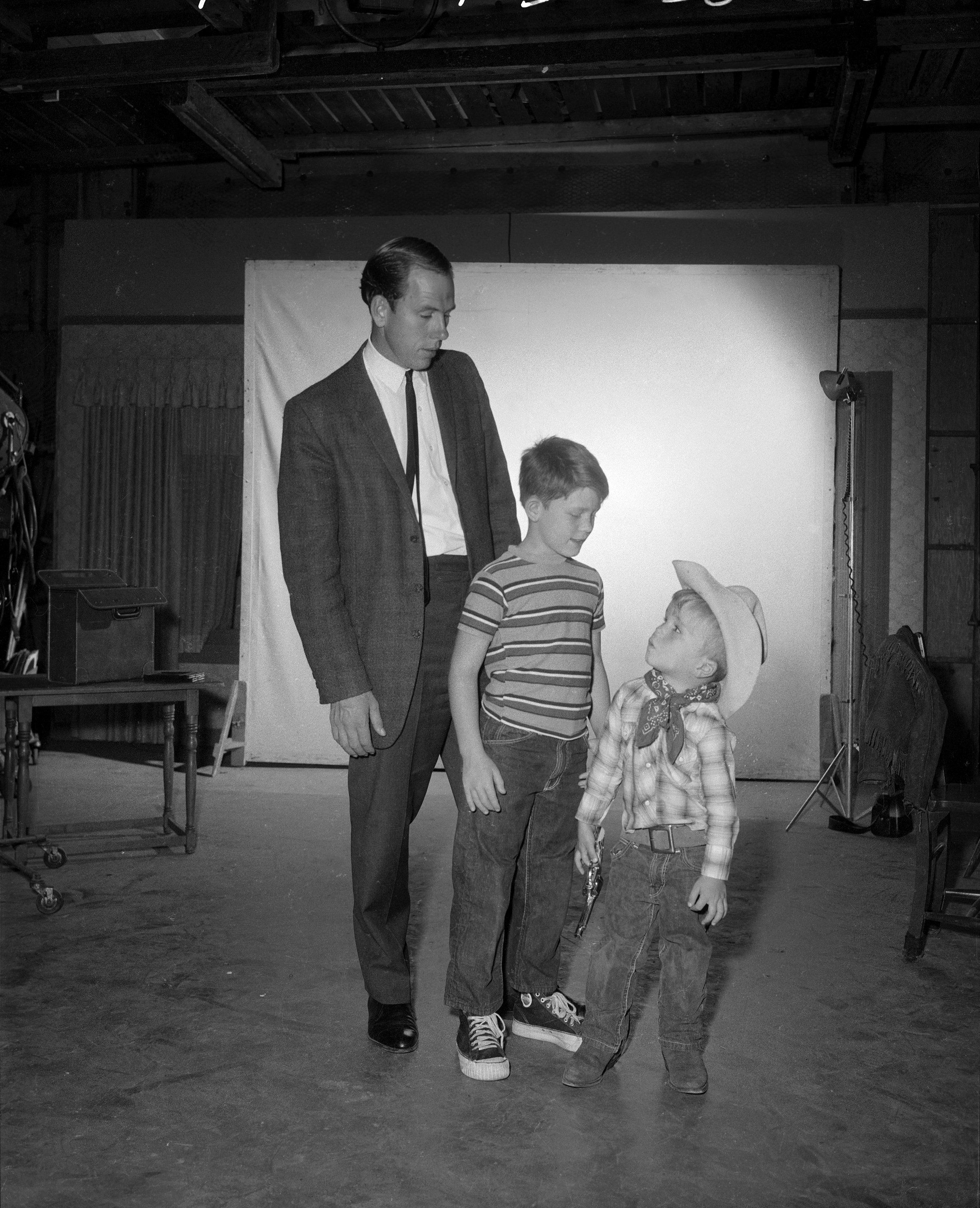 On 'The Andy Griffith Show' set: Rance Howard, Ron Howard, and Clint Howard pose glance towards one another in this posed photograph.