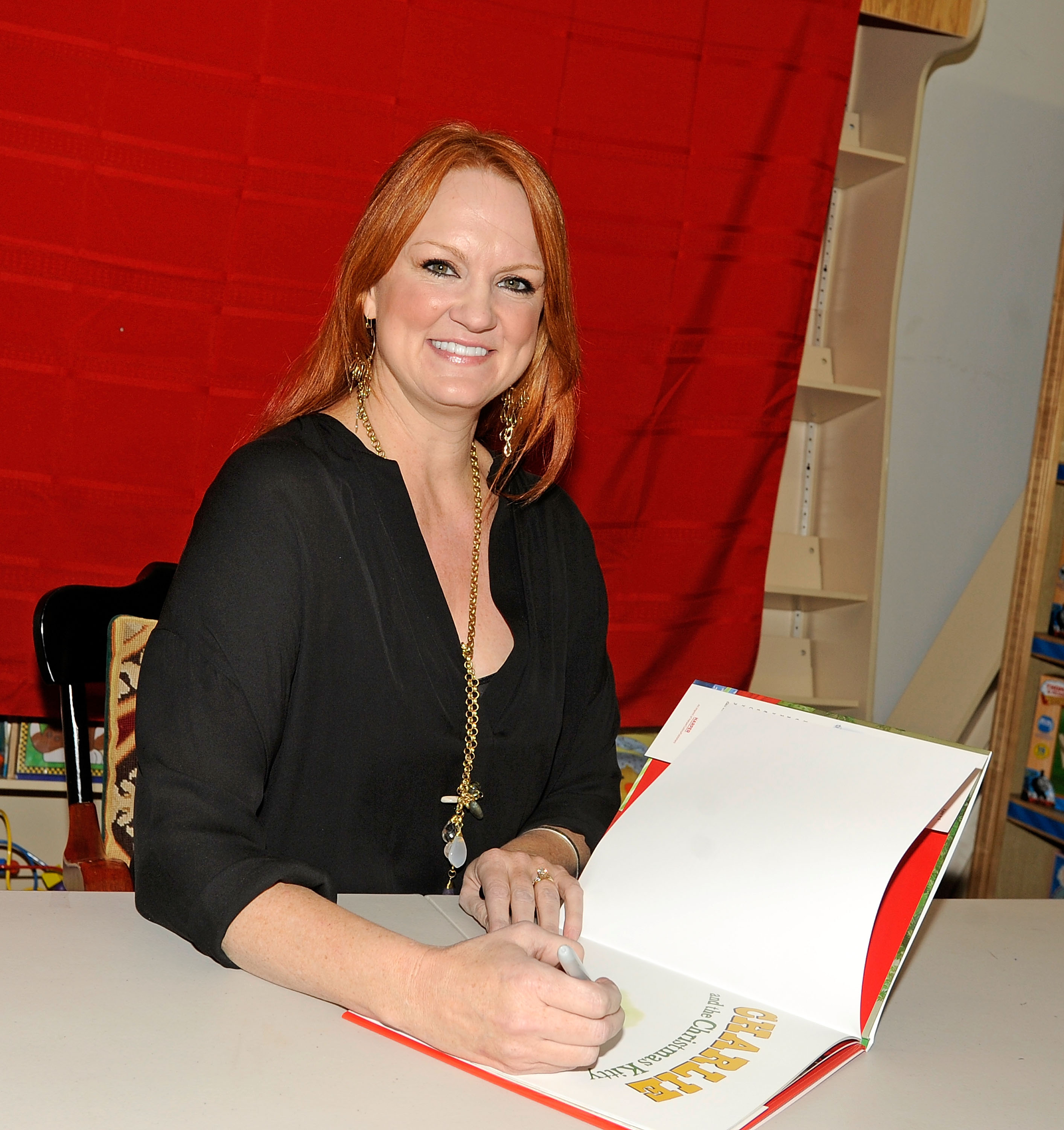 The Pioneer Woman Ree Drummond smiles as she signs a cookbook at a 2012 book signing