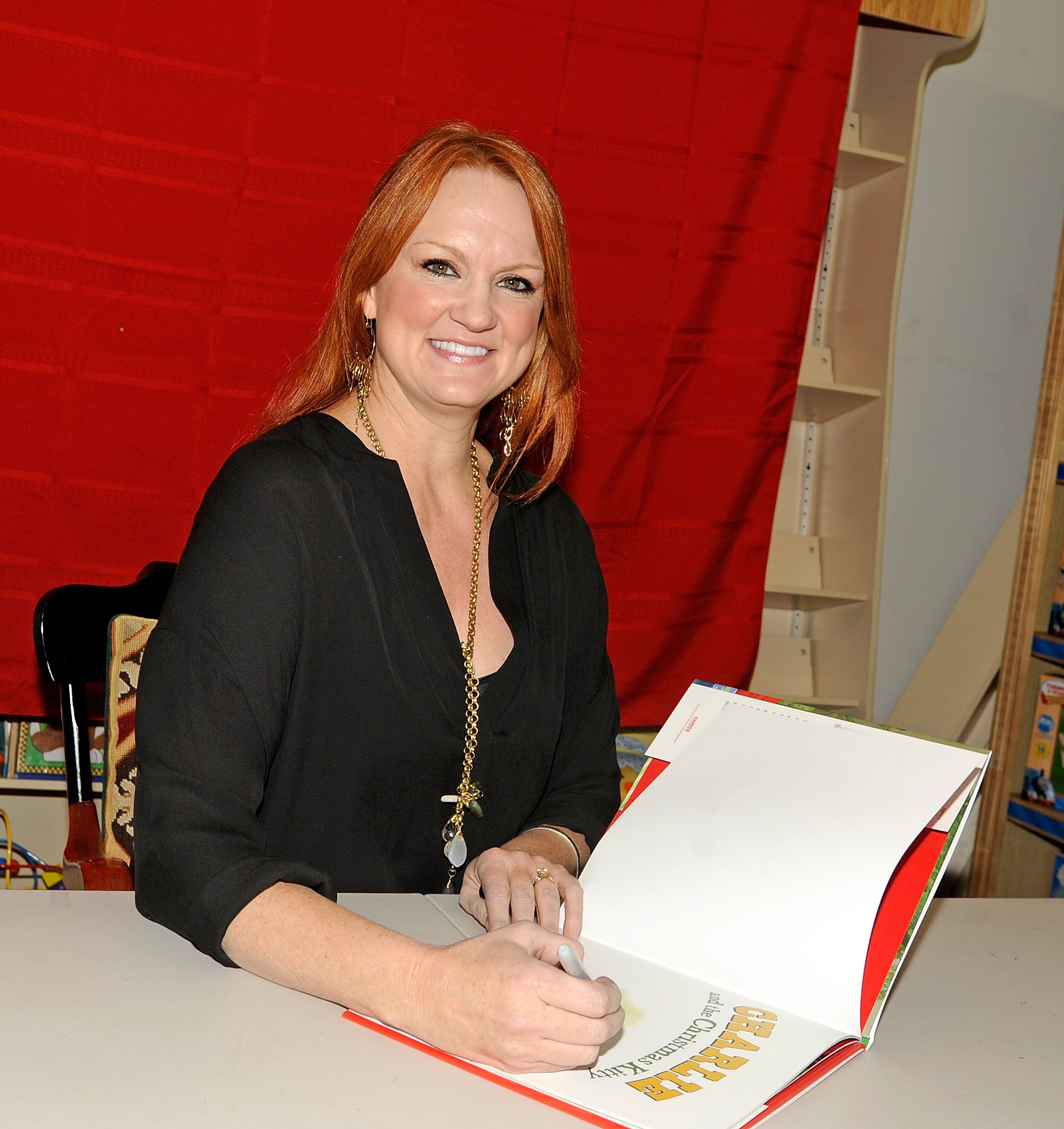 The Pioneer Woman Ree Drummond smiles as she signs a cookbook at a 2012 book signing