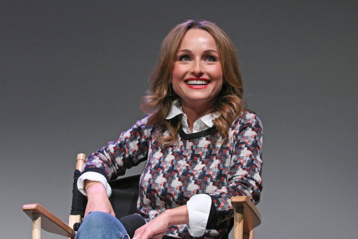 Food Network star Giada De Laurentiis smiles at a public appearance in a multi-colored sweater and jeans.