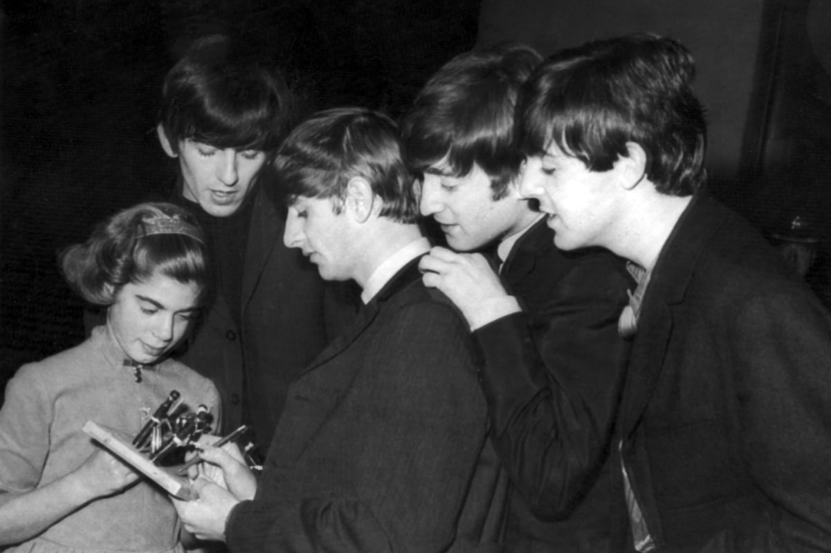 Ringo Starr, third from left, signs an autograph for a young fan as his fellow Beatles (left to right) George Harrison, John Lennon, and Paul McCartney look on in 1963