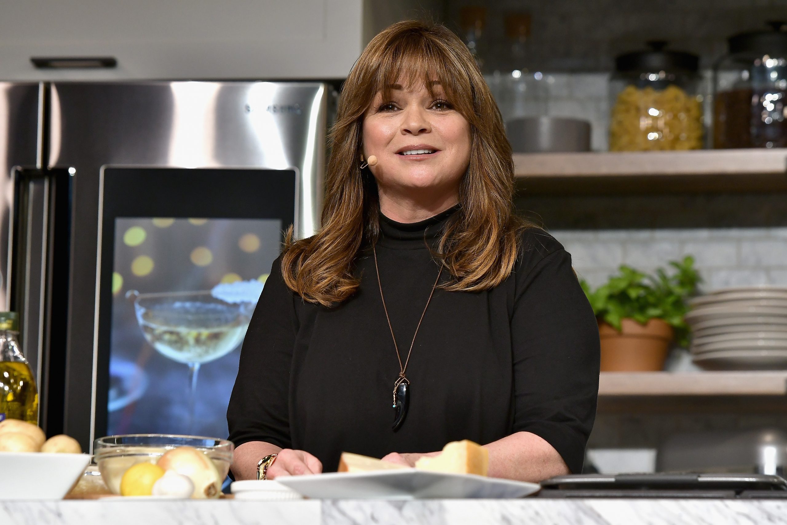 Food Network star Valerie Bertinelli is in a long-sleeved black top as she prepares a recipe.