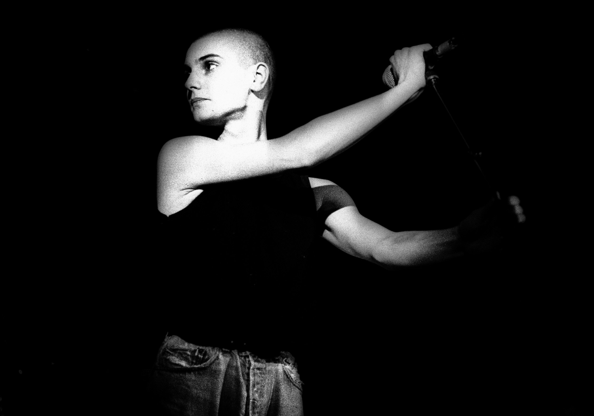 Irish singer Sinéad O'Connor holds a microphone stand in concert in 1988