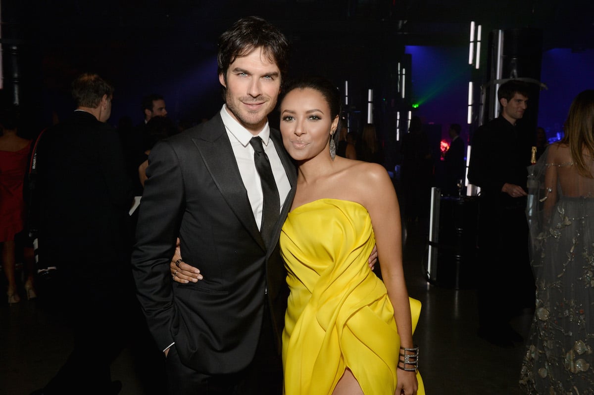 Ian Somerhalder wears a black suit and tie posing with Kat Graham, who wears a yellow gown.