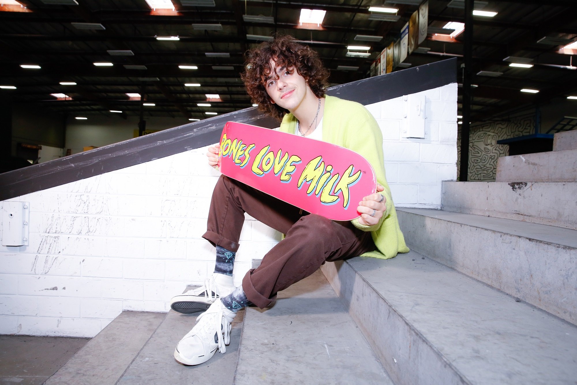 Jack Dylan Grazer sits holding a skateboard