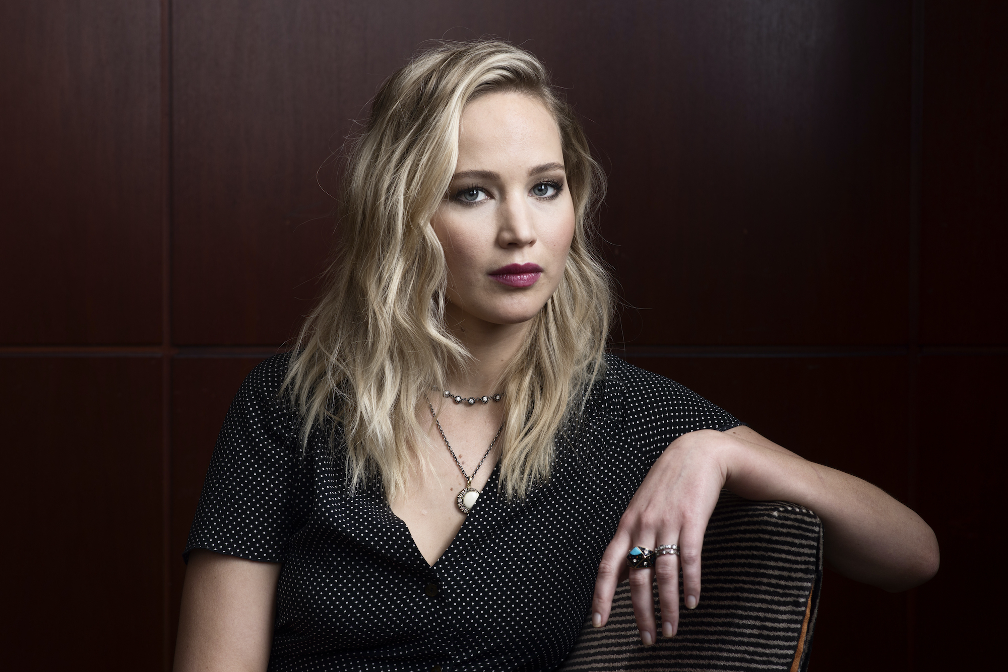 Jennifer Lawrence smiling in front of a wood paneled wall