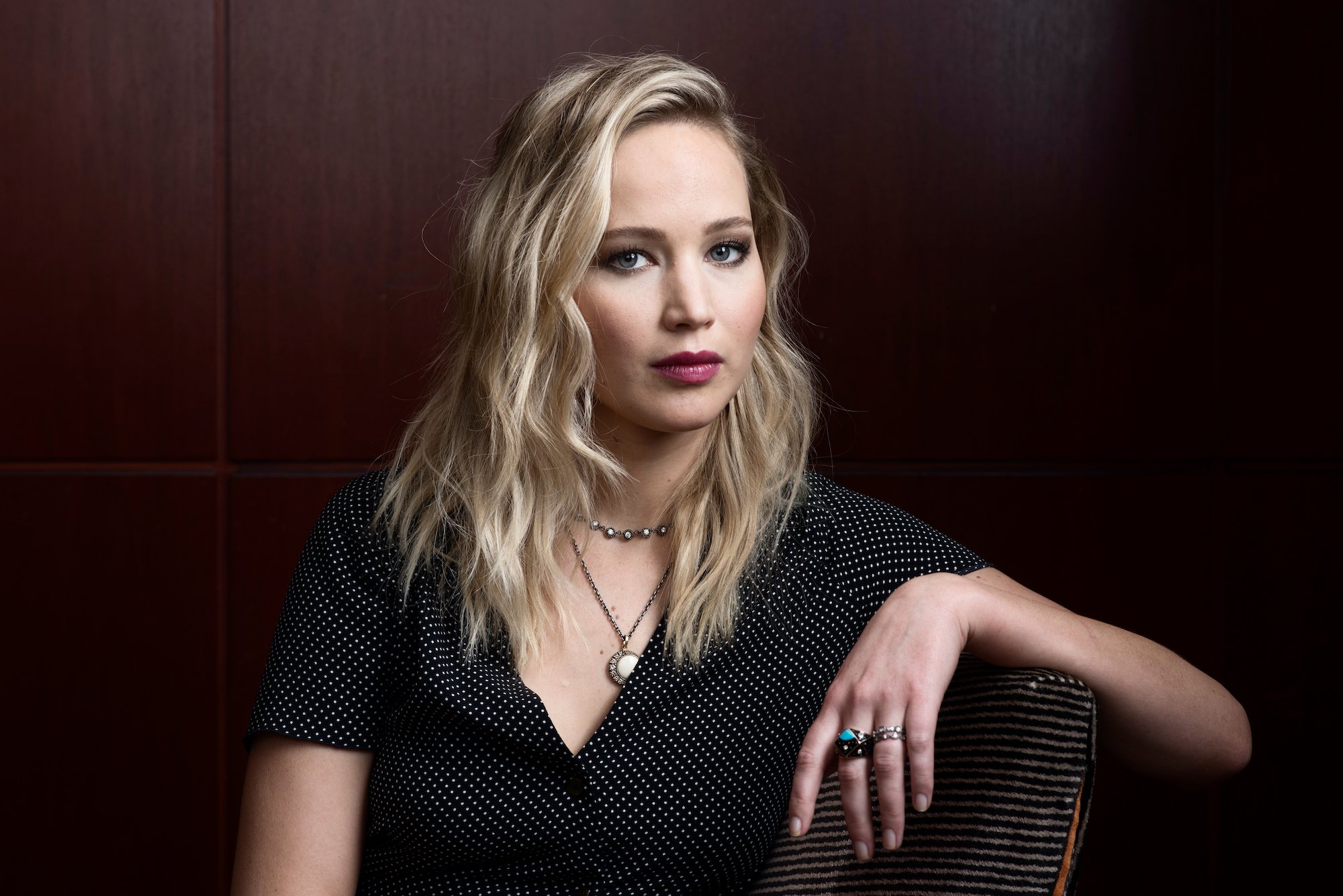 Jennifer Lawrence smiling in front of a wood paneled wall