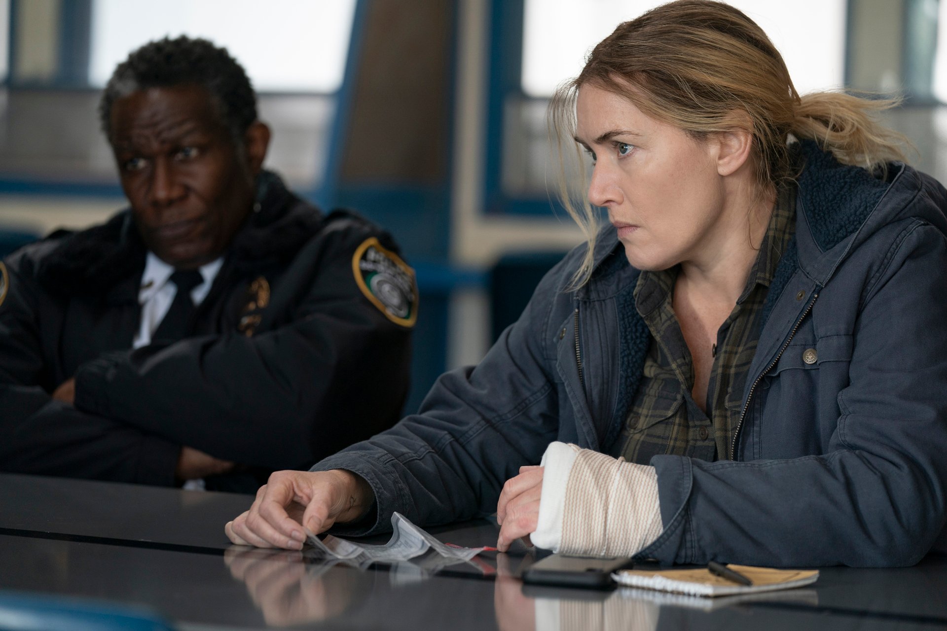 John Douglas Thompson and Kate Winslet sit at a desk in 'Mare of Easttown'