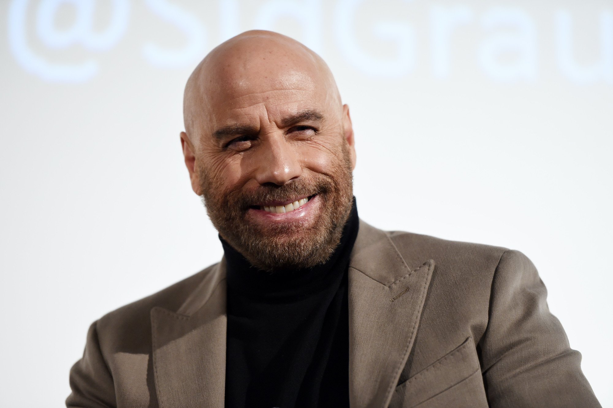 John Travolta smiling in front of a white background