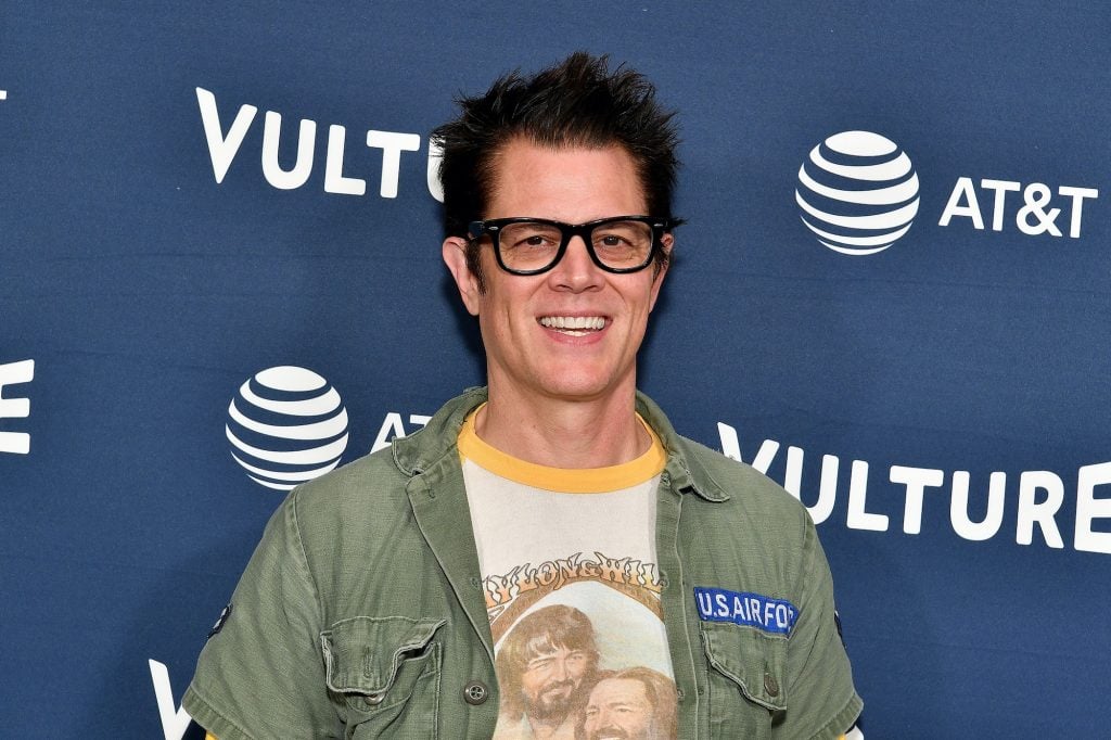 Johnny Knoxville smiling in front of a blue background