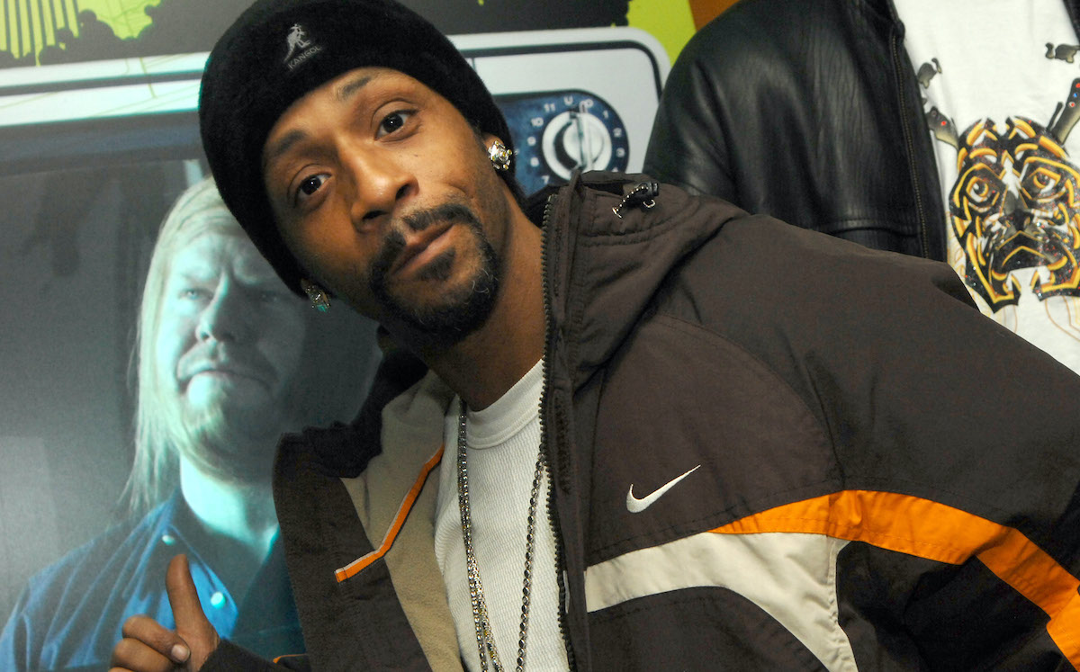 Katt Williams at an event, leaning over and pointing to a promotional image