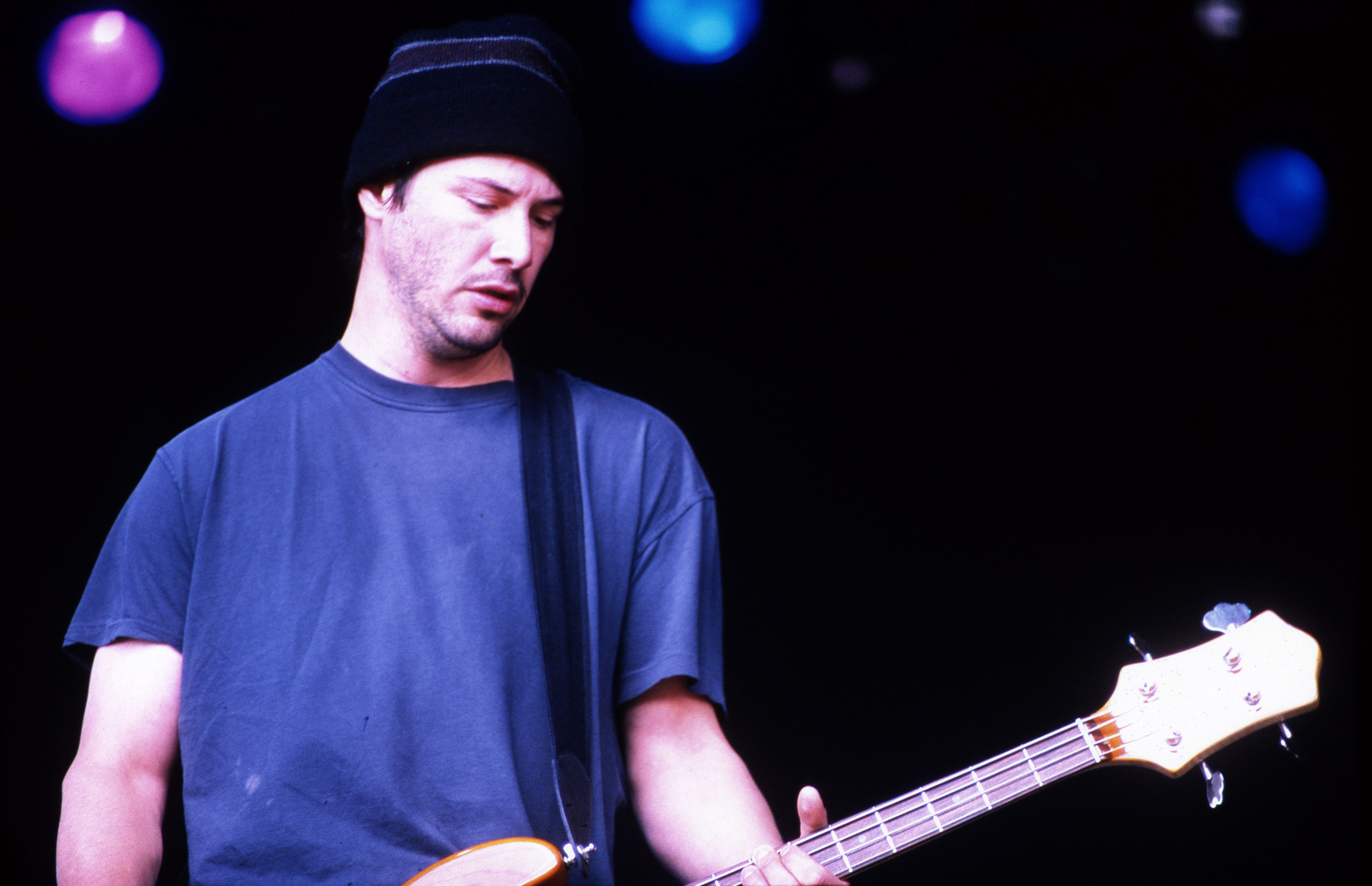 Keanu Reeves playing guitar on stage