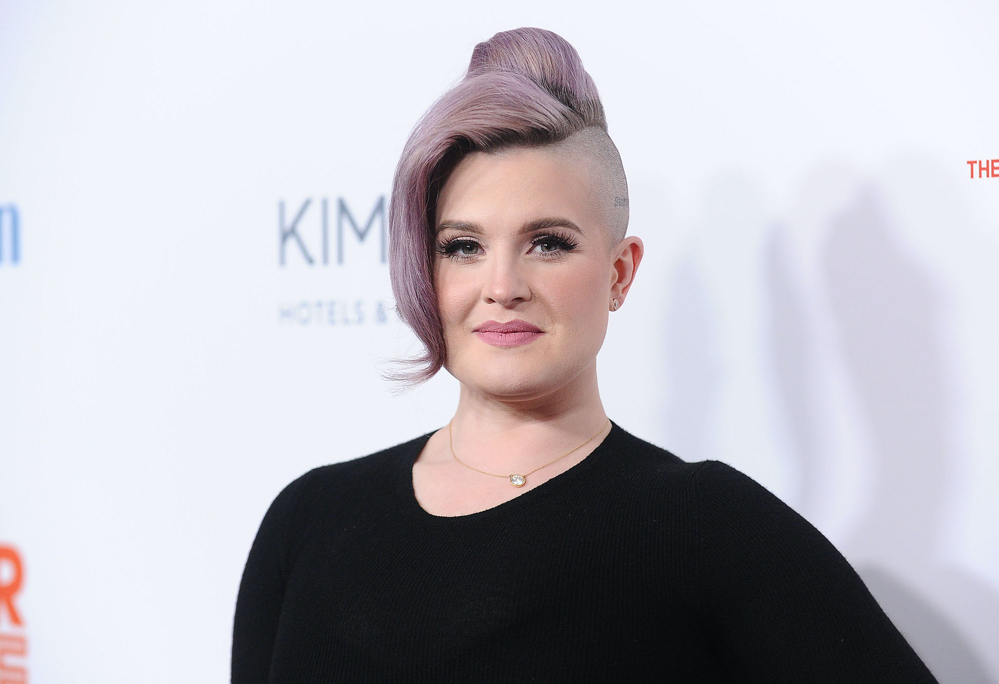 Kelly Osbourne smiling in front of a white background